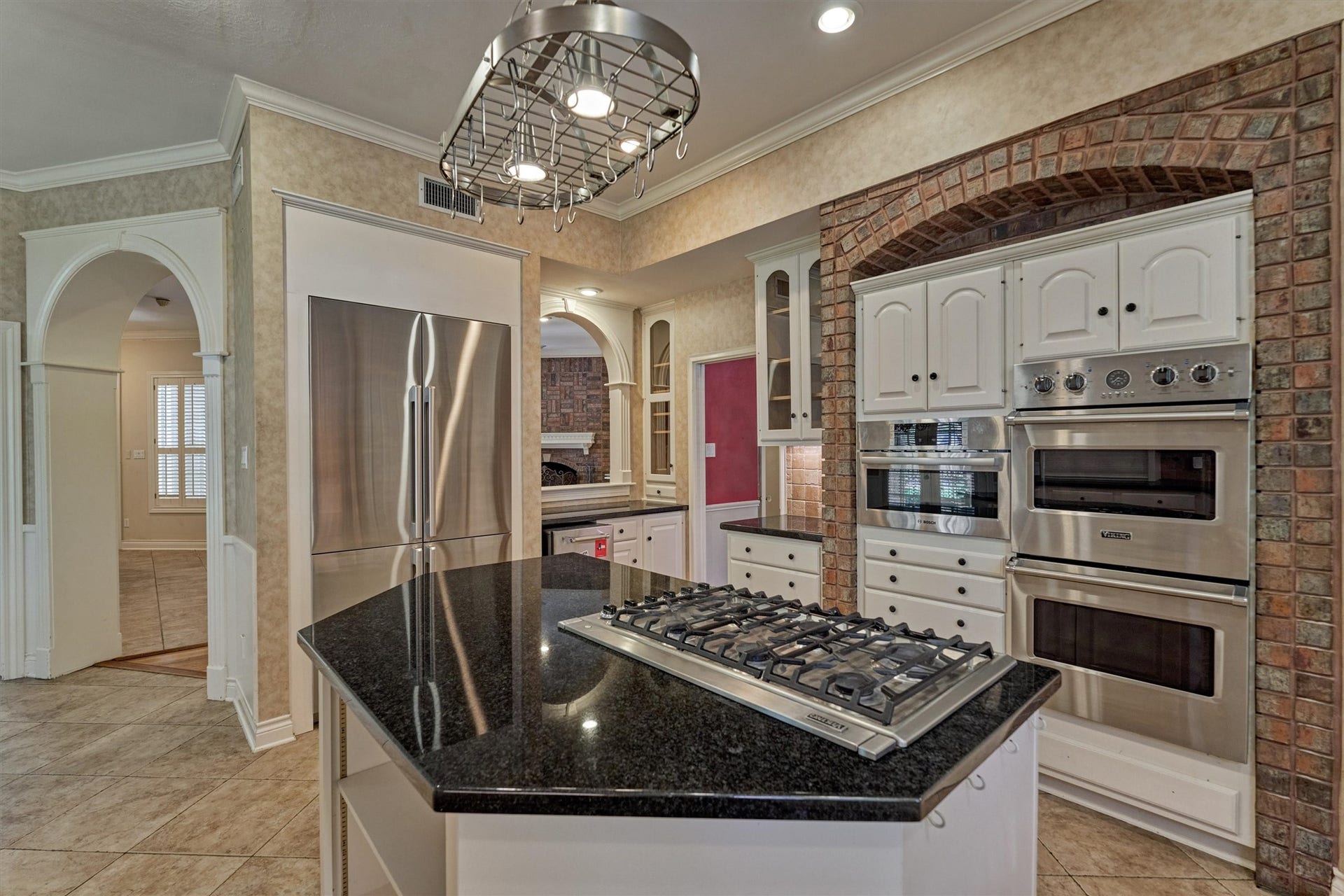 26 S Brokenfern Drive, The Woodlands, TX 77380 Cook and entertain in style in this chefs kitchen, featuring granite countertops, Viking stainless appliances, and a large island with a gas cooktop. Tile floors, plenty of cabinet storage, and an open sightline to the family room keep the cook connected to the action. The brick-arched oven niche adds warmth and character.
