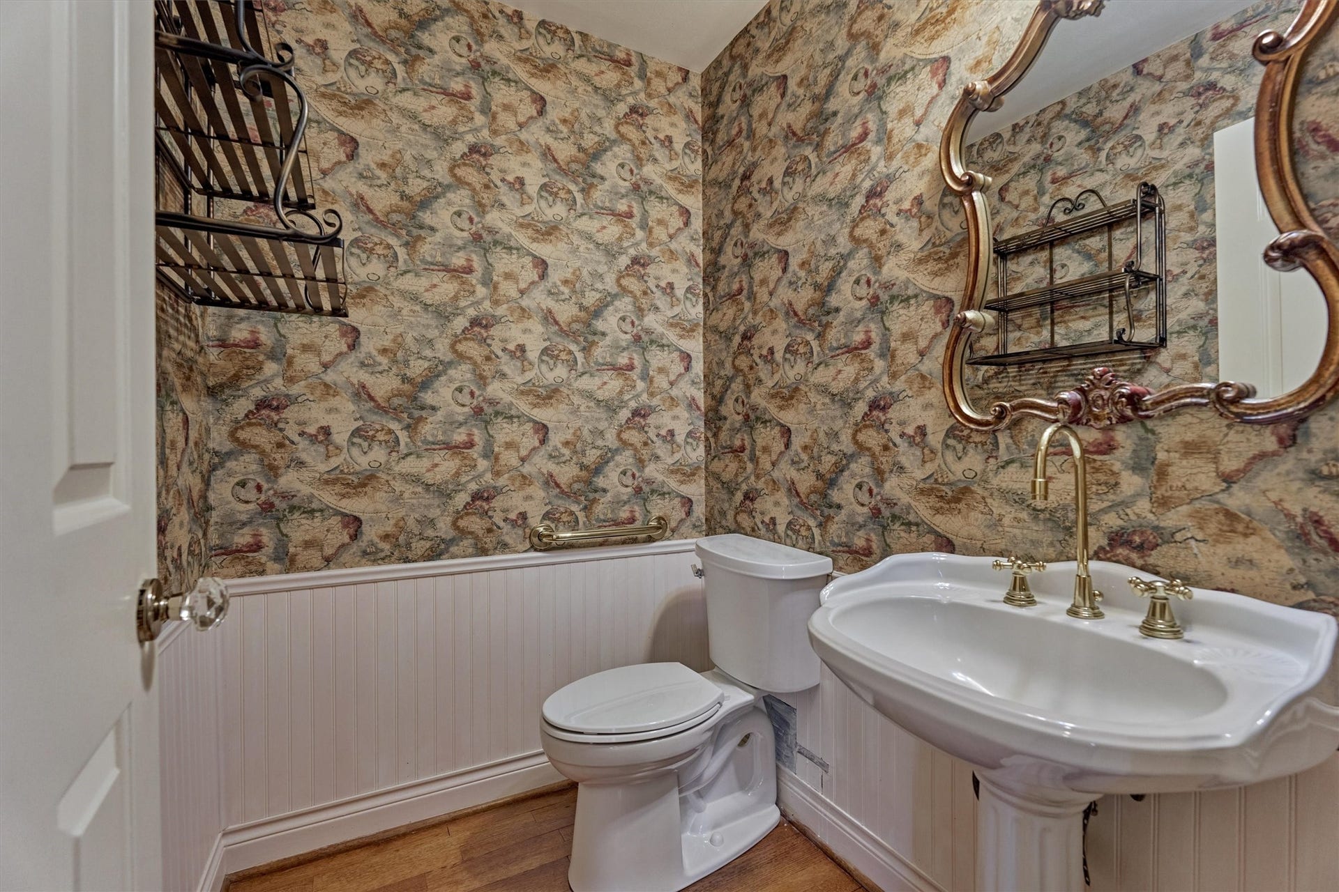 26 S Brokenfern Drive, The Woodlands, TX 77380 Guests will appreciate this convenient bath, located across from the primary bedroom and open to the office. A pedestal sink with brass fixtures, beadboard wainscoting, and hardwood floors give it a classic, polished look. It works well for visitors and for anyone using the office.