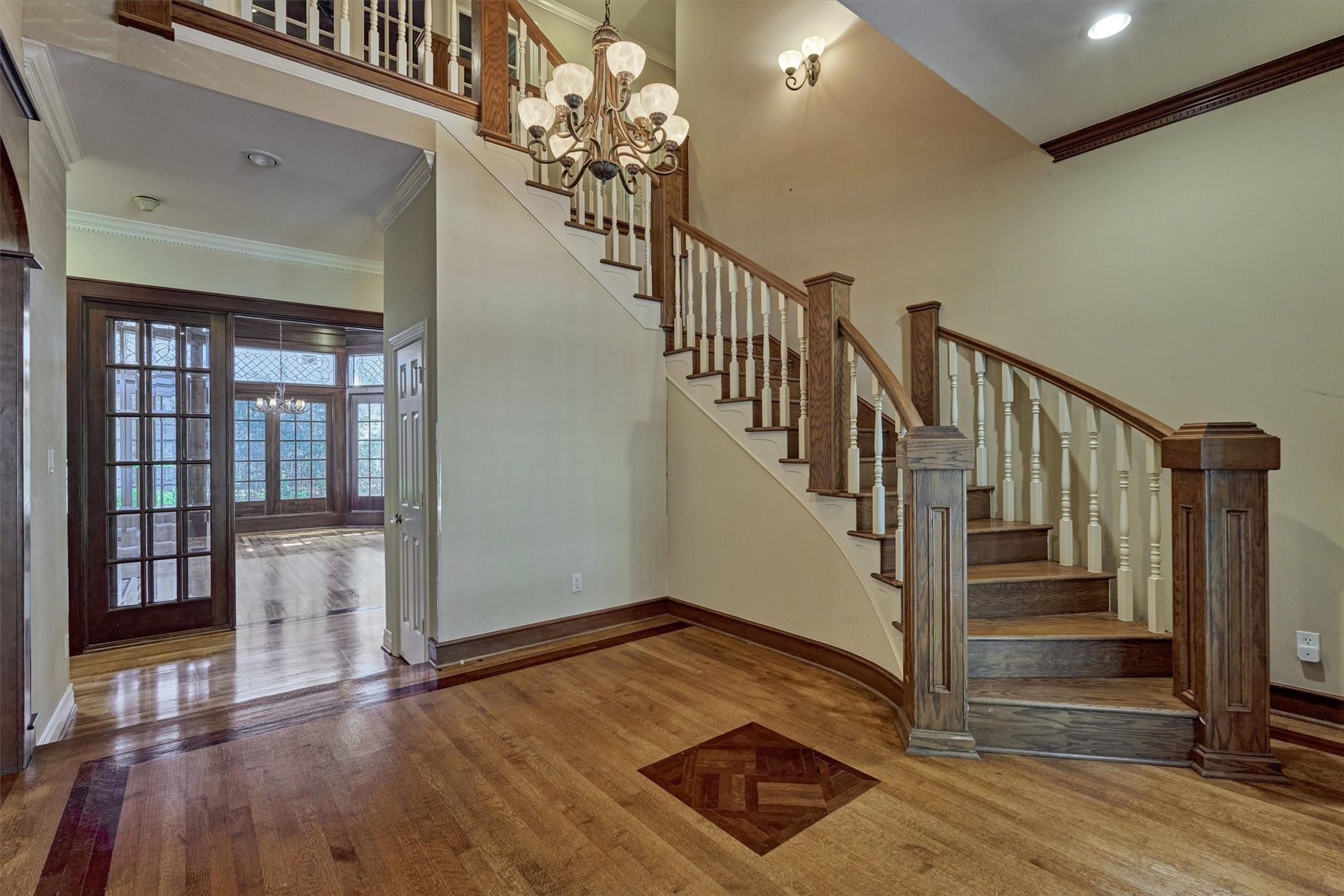 26 S Brokenfern Drive, The Woodlands, TX 77380 Make a grand first impression in this soaring foyer with its curved staircase, hardwood floors, and gracious chandelier. The open sightline through French doors leads to the library beyond, creating a seamless flow for entertaining and everyday living. A second-floor balcony overlooks the entry, adding to the sense of openness.