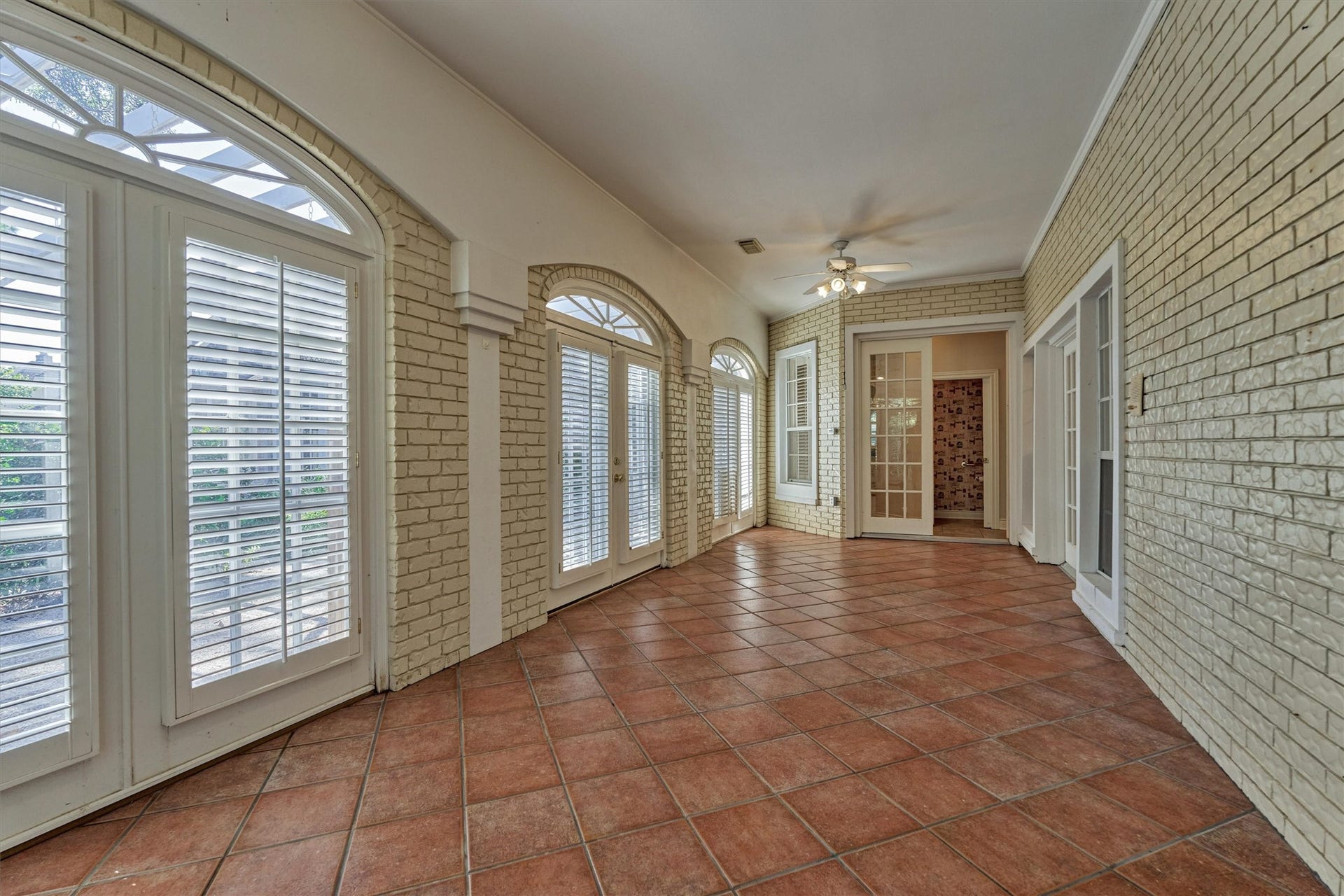 26 S Brokenfern Drive, The Woodlands, TX 77380 Another angle of the sunroom shows how much natural light this long, flexible space gets. Arched windows and shuttered French doors line the curved wall and look out to the backyard, and the tile floors are easy to maintain. Use it as a game room, sitting area, or hobby space, with direct access to the secondary downstairs suite at the far end. Large closet holds a wine refrigerator.
