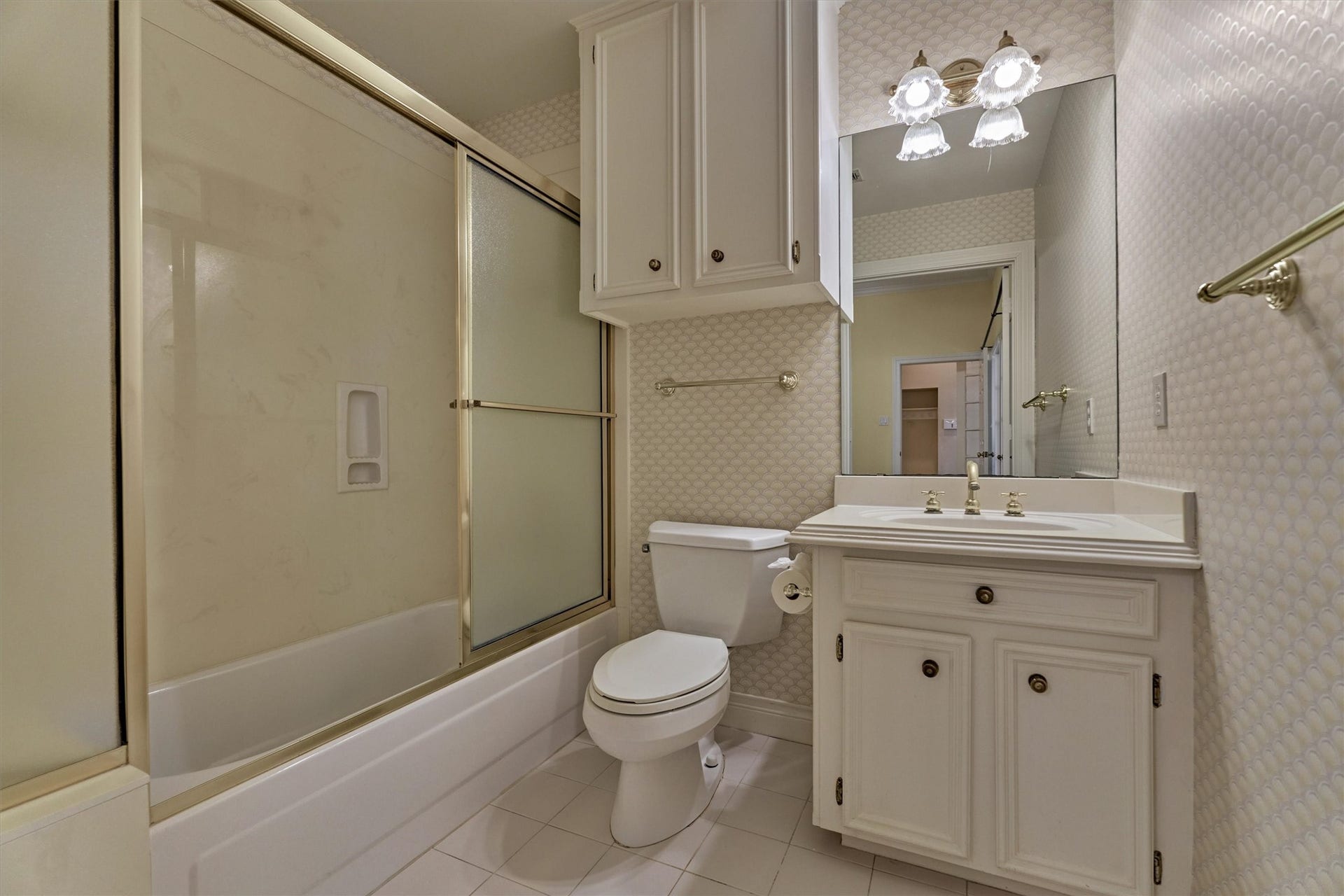 26 S Brokenfern Drive, The Woodlands, TX 77380 This private bath in the secondary suite is convenient and comfortable. A tub and shower combination, a single-sink vanity with cabinet storage, and extra overhead cabinets keep everything within reach. Bright, easy-care tile floors and a mirror with a multi-light fixture make it a practical space for guests, in-laws, or family.