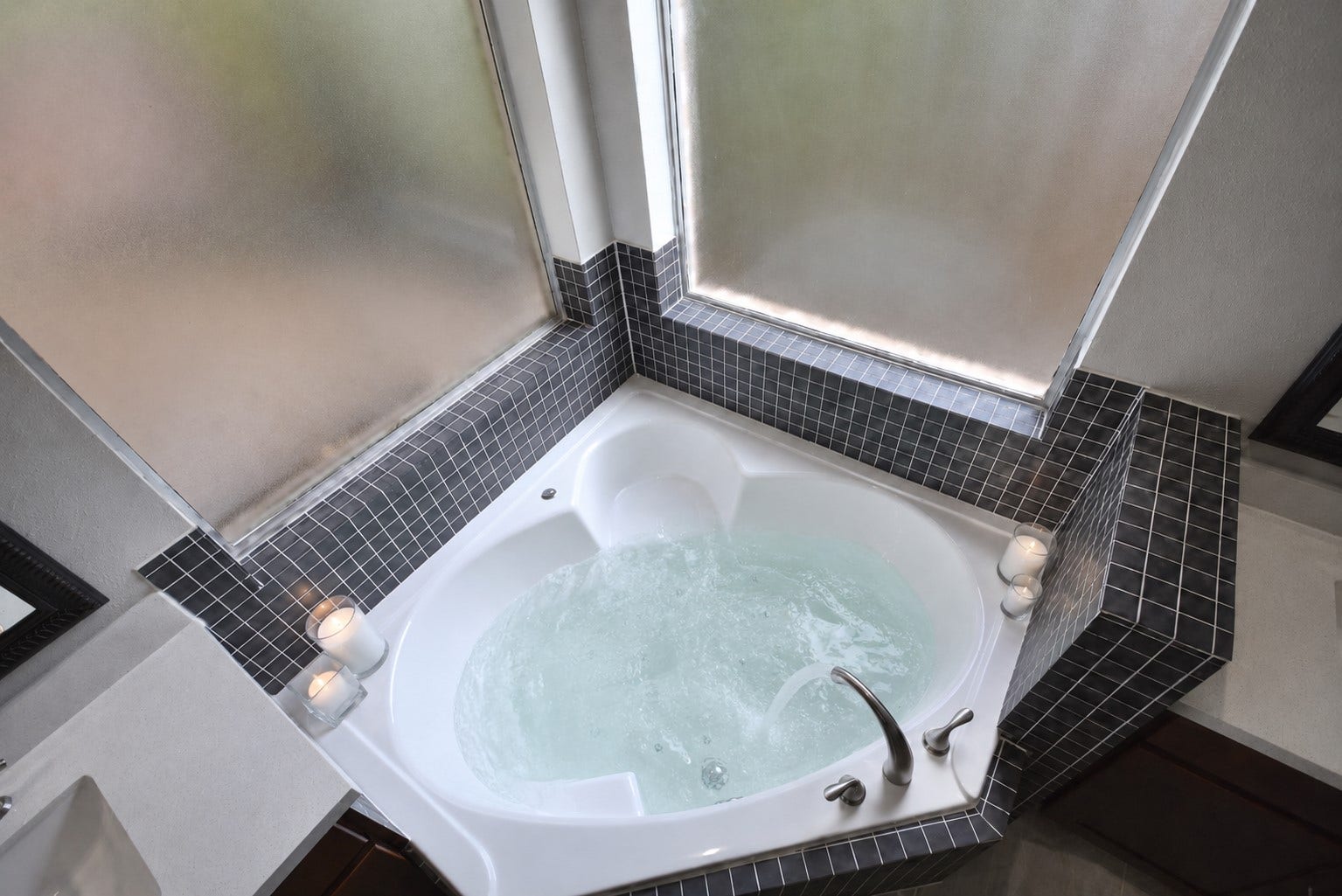 Unwind in your luxurious corner whirlpool tub and let the soothing bubbles melt away the stress of the day. Designed with comfort in mind, the tub features a convenient built-in seating ledge, perfect for relaxation and everyday convenience. Frosted glass windows fill the spa-inspired bathroom with beautiful natural light while maintaining your privacy, creating the perfect retreat to relax, recharge, and enjoy your own personal sanctuary.