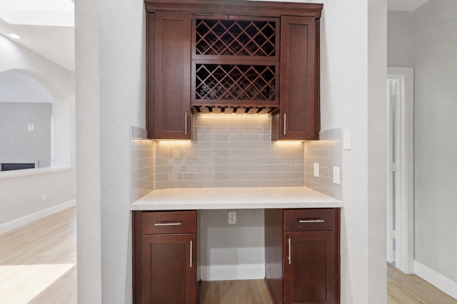 Entertain in style with this stunning beverage and serving bar, featuring gorgeous sparkling quartz countertops, a sleek glass tile backsplash, beautiful tall custom cabinetry, a built-in wine glass holder, and a convenient wine rack. Designed for both elegance and functionality, it's the perfect gathering spot for hosting family celebrations and entertaining friends. This beautifully remodeled home is ready for its next owner. Have you picked up the phone yet?
