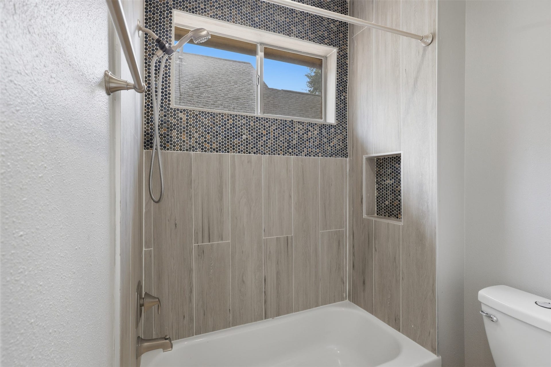 The Jack-and-Jill bathroom features a beautiful tub and shower combination accented by gorgeous custom tile surround, creating a timeless and elegant look. Thoughtfully designed with quality finishes and exceptional craftsmanship, this inviting bathroom offers both style and functionality for family and guests alike.