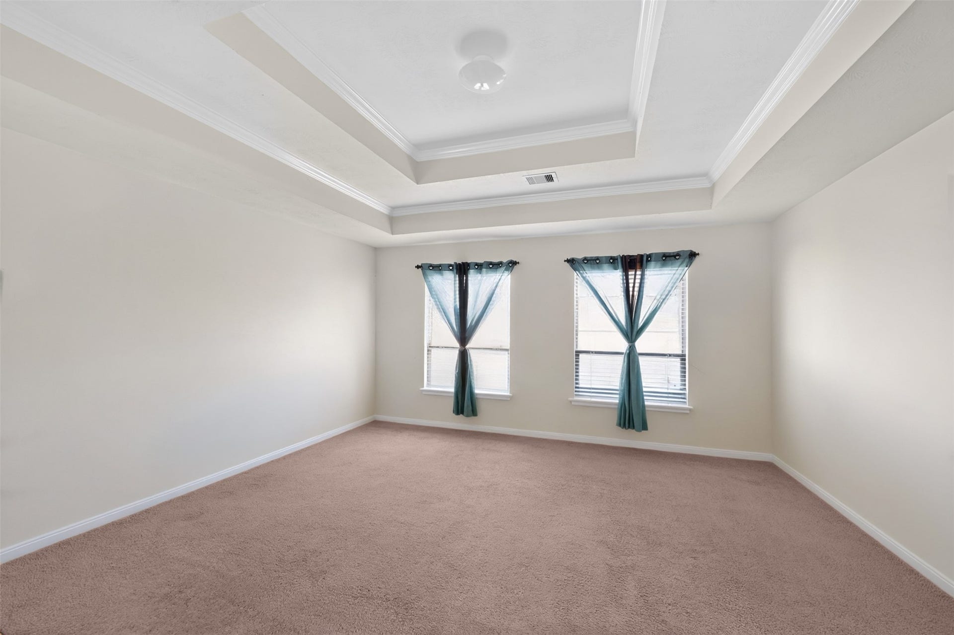 Peaceful primary suite featuring tray ceilings and plenty of room for a sitting area.