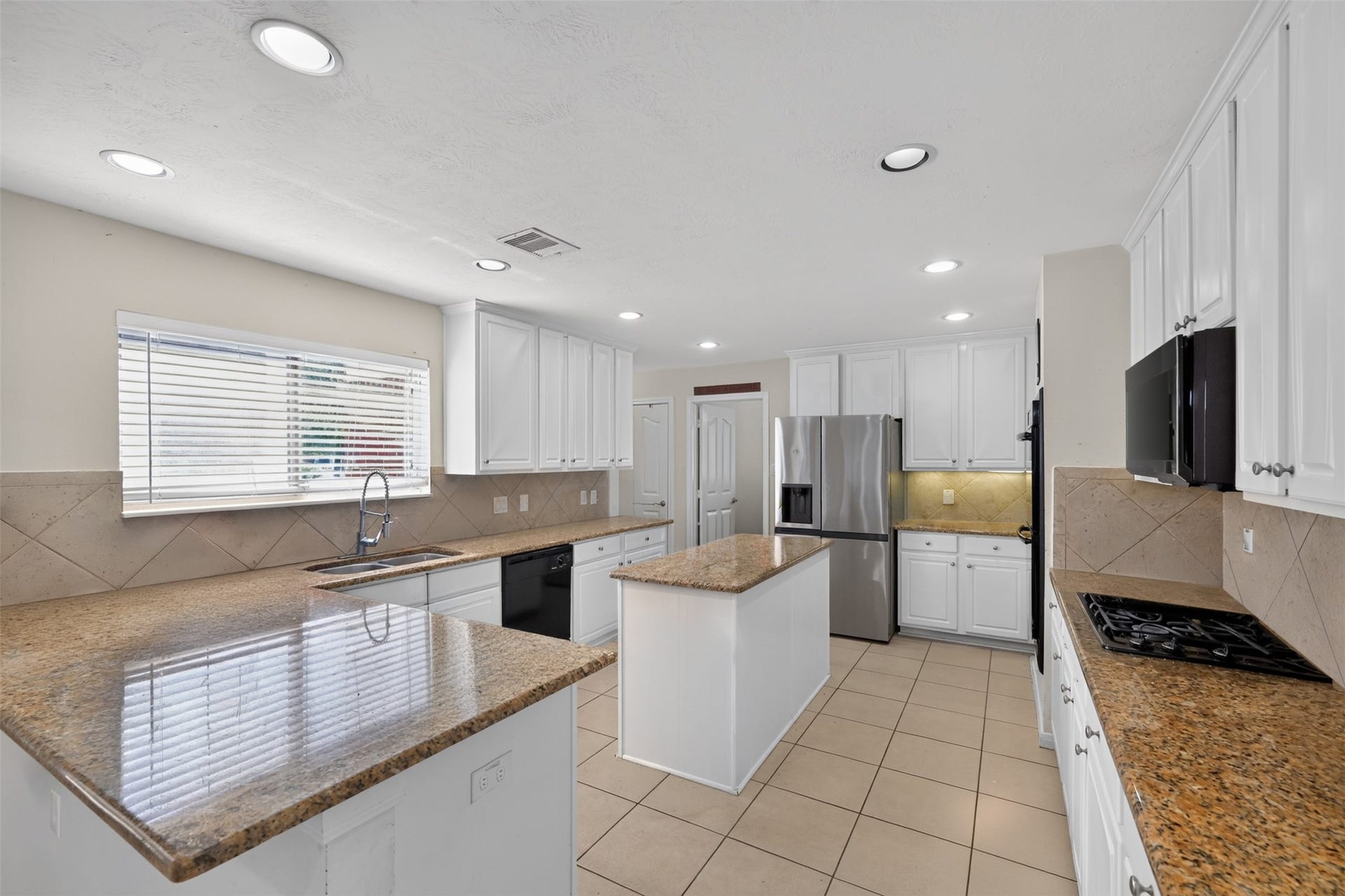 Large island kitchen with abundant counter space, extensive cabinetry, and stainless steel appliances.