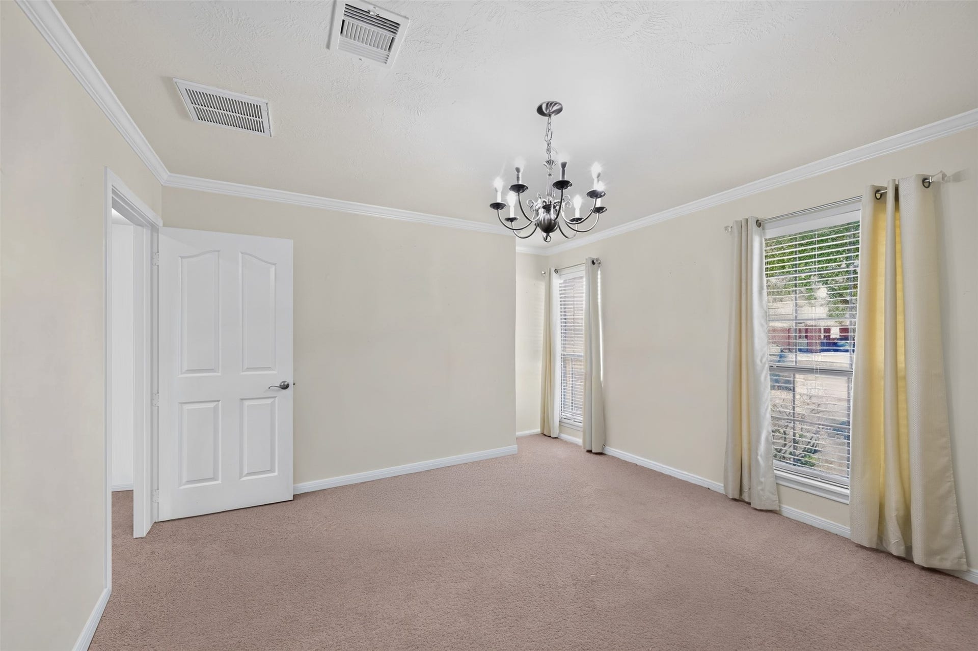 Elegant formal dining room with chandelier and views of the front yard.