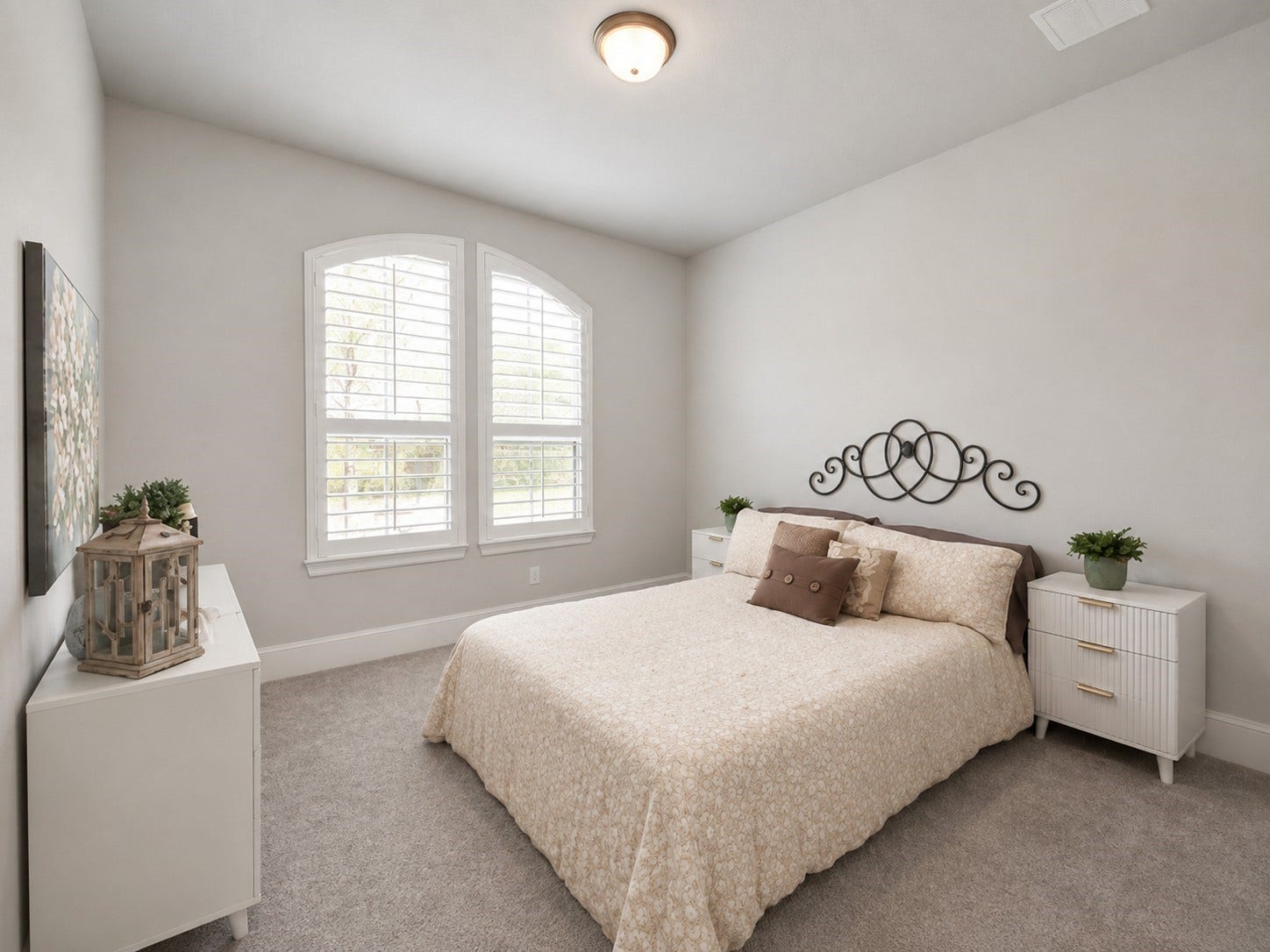 Bright downstairs secondary bedroom with soft neutral tones, features a walk-in closet, and ample natural light from stylish plantation shutter windows.