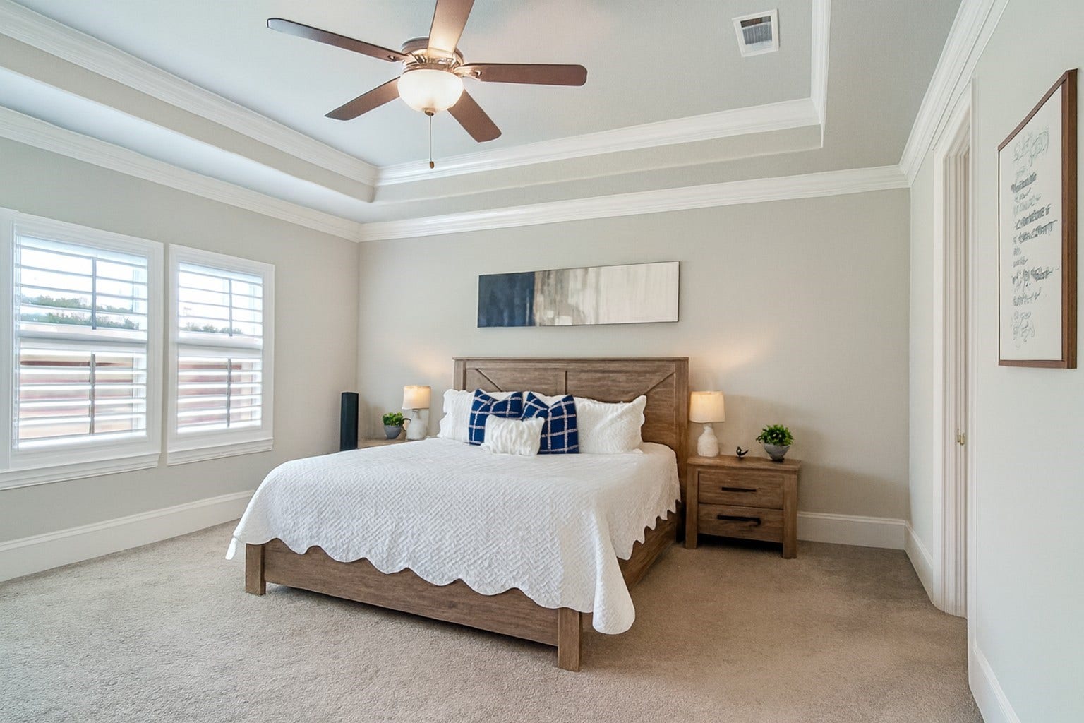 This downstairs primary bedroom has upgraded crown molding in the tray ceiling and overlooks the beautifully landscaped backyard.