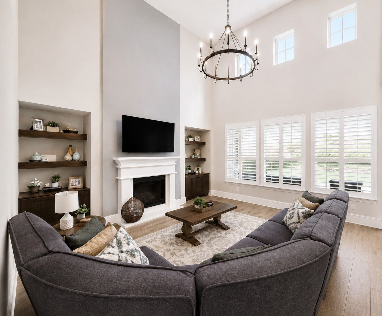 The main living/family room, with 2 story ceilings, has built-in cabinets and floating shelves, a cozy gas log fireplace, plus an updated cohesive light fixture to complete the space.