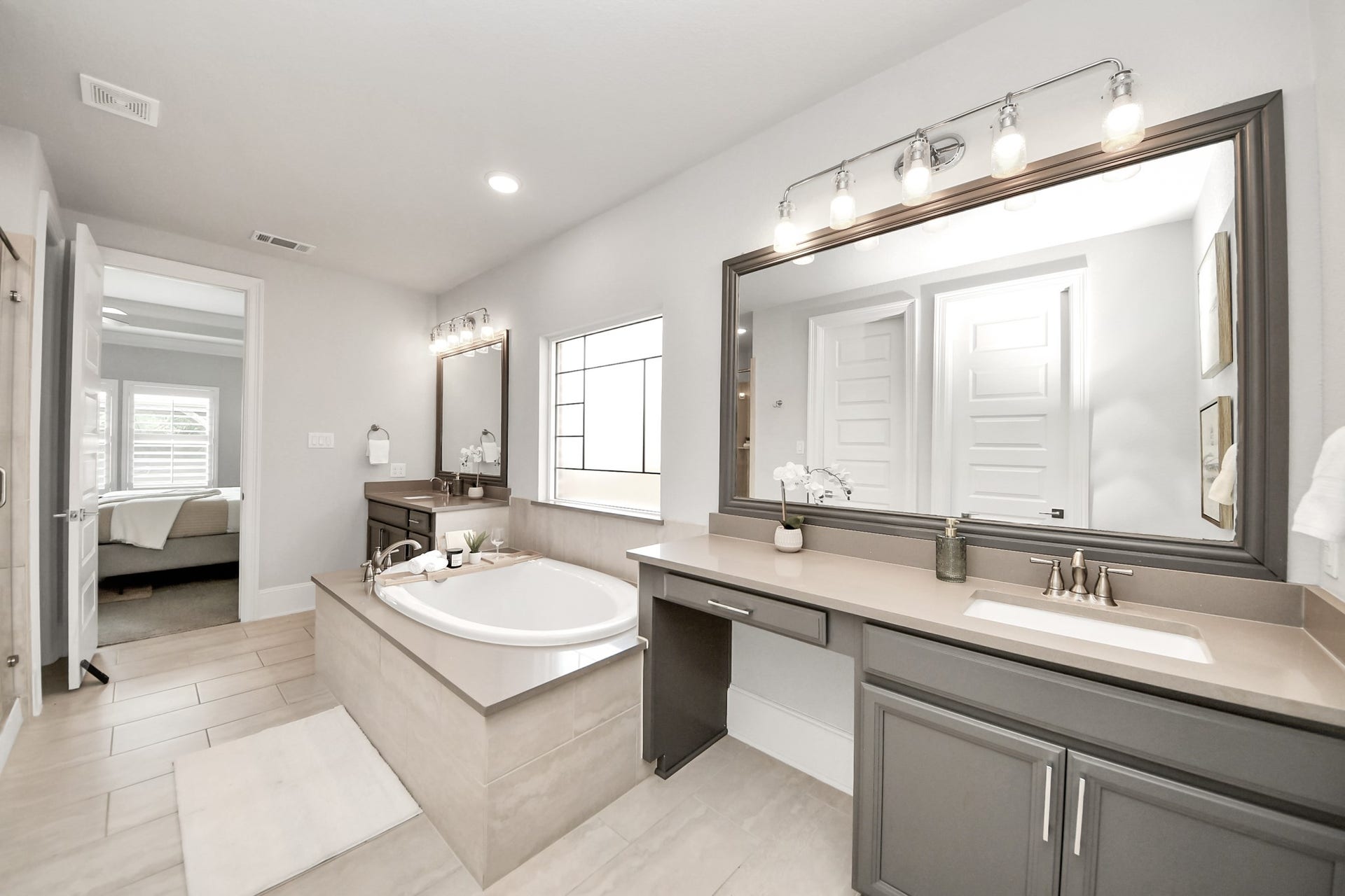 Another view of the primary bathroom with upgraded lighting, framed mirrors, an enclosed toilet area, and 2 closets.