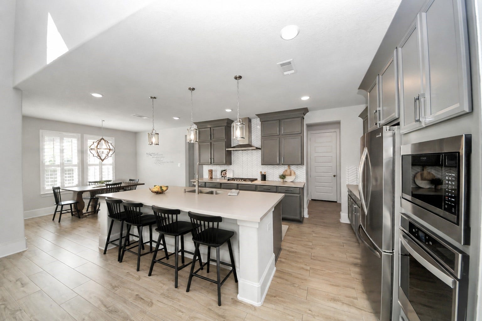 Bright and spacious kitchen with modern stainless steel appliances, a large center island with seating, and elegant pendant lighting.