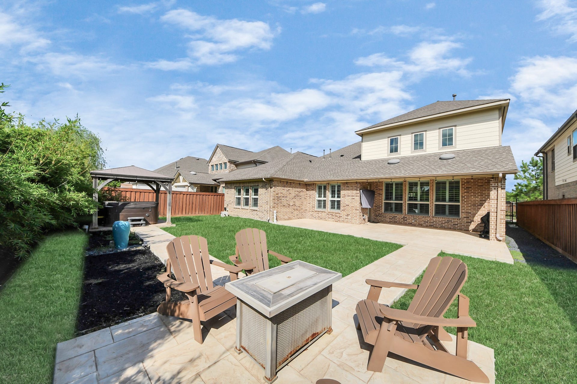 Spacious backyard featuring a well-maintained lawn, cozy seating area with a fire pit, and a charming gazebo.