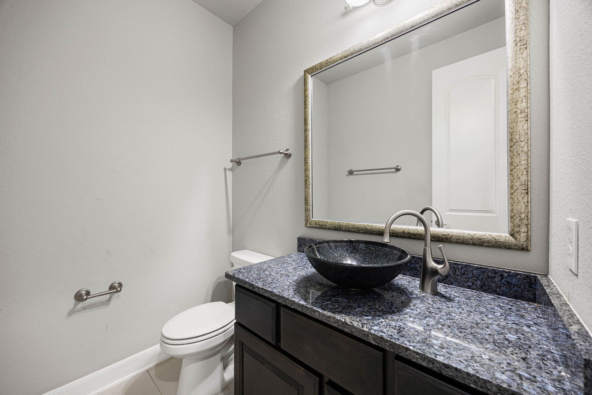 10606 Comeaux Lane, Richmond, TX 77407 A striking vessel sink in speckled glass tops the granite vanity in this secondary bath, paired with a sleek gooseneck faucet for a modern, upgraded touch.