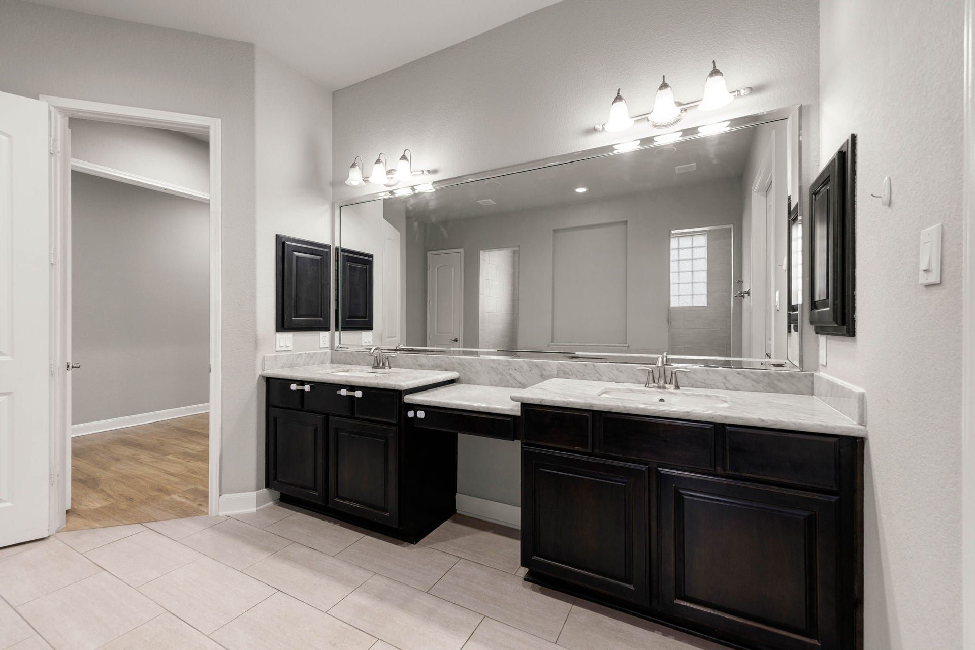 10606 Comeaux Lane, Richmond, TX 77407 This primary ensuite features a dual-sink vanity with marble counters, a private makeup vanity space, and dark wood cabinetry for a polished, modern look.