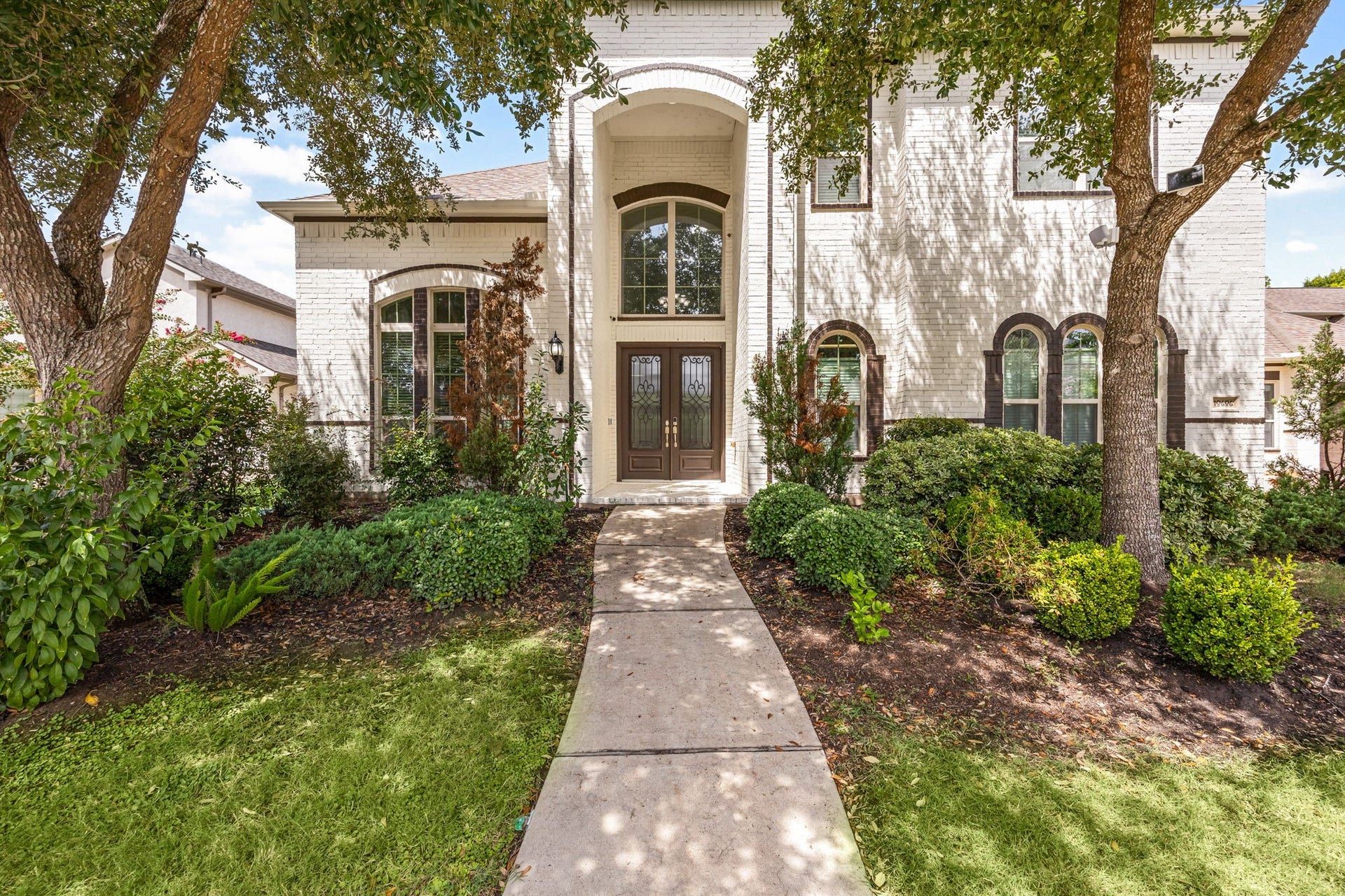 10606 Comeaux Lane, Richmond, TX 77407 A closer look at the front entrance highlights the homes distinctive arched architecture, stately double doors, and mature landscaping that frames the approach.