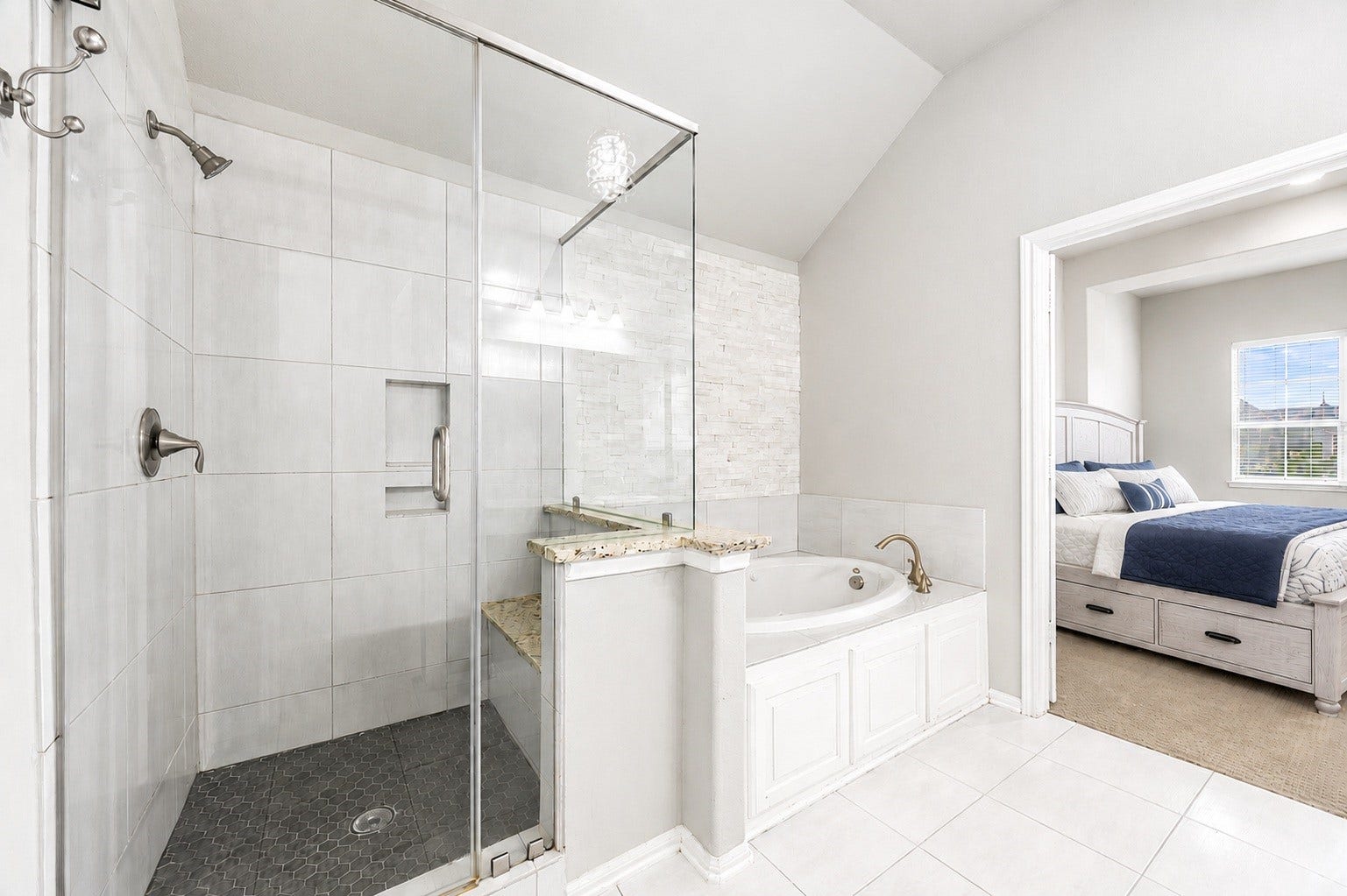 10606 Comeaux Lane, Richmond, TX 77407 This ensuite pairs a walk-in glass shower with a jetted soaking tub set beneath a stacked-stone accent wall, offering direct access to the second primary suite.