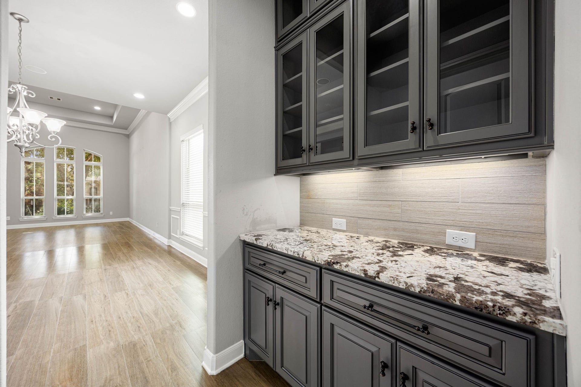 10606 Comeaux Lane, Richmond, TX 77407 A butler's pantry connects the kitchen and dining area, offering striking counters and glass-front cabinetry for extra storage and easy serving between spaces.