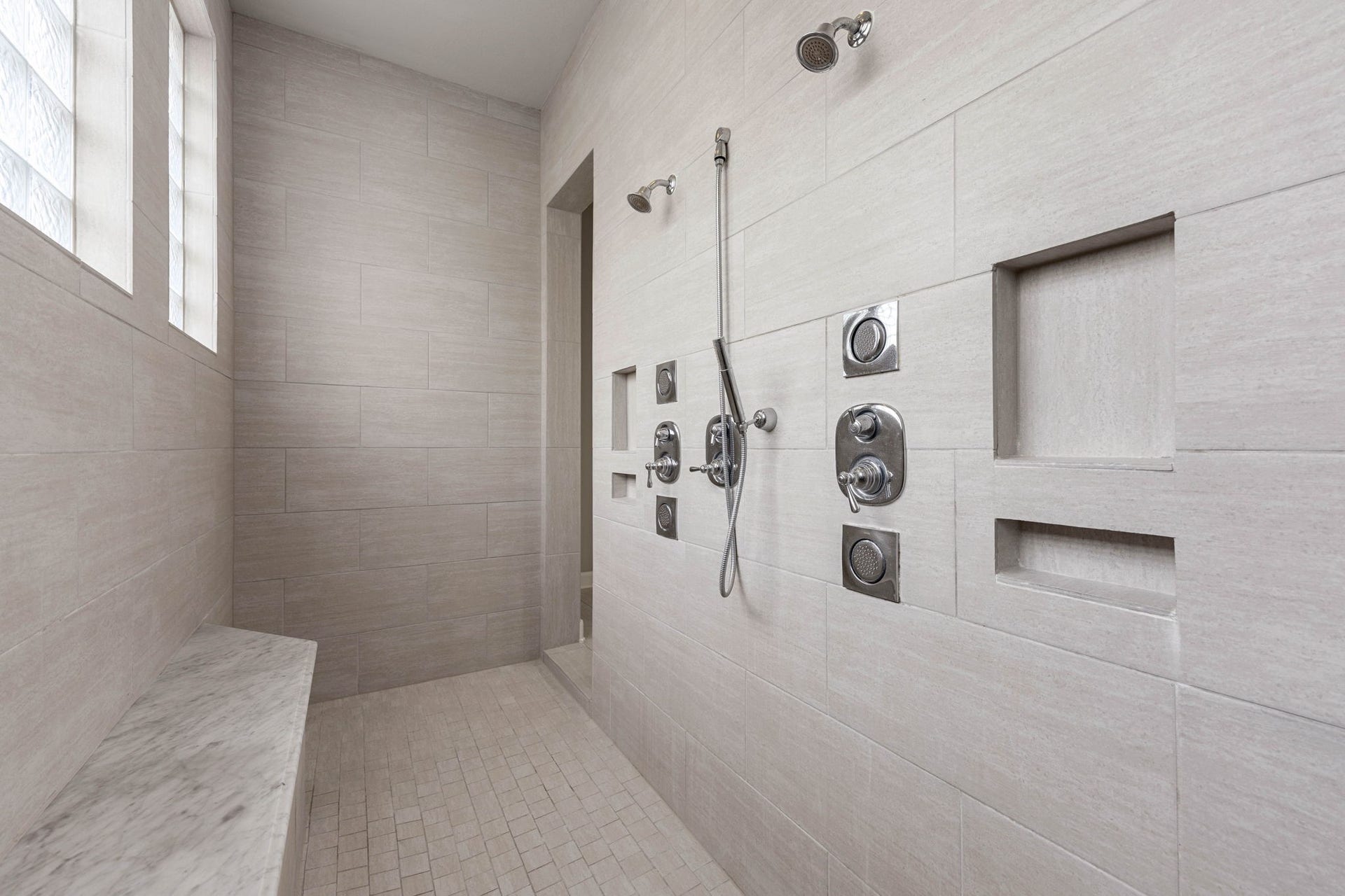 10606 Comeaux Lane, Richmond, TX 77407 The oversized walk-in shower features dual shower heads, a handheld sprayer, and built-in niches, offering a spacious, modern showering experience.