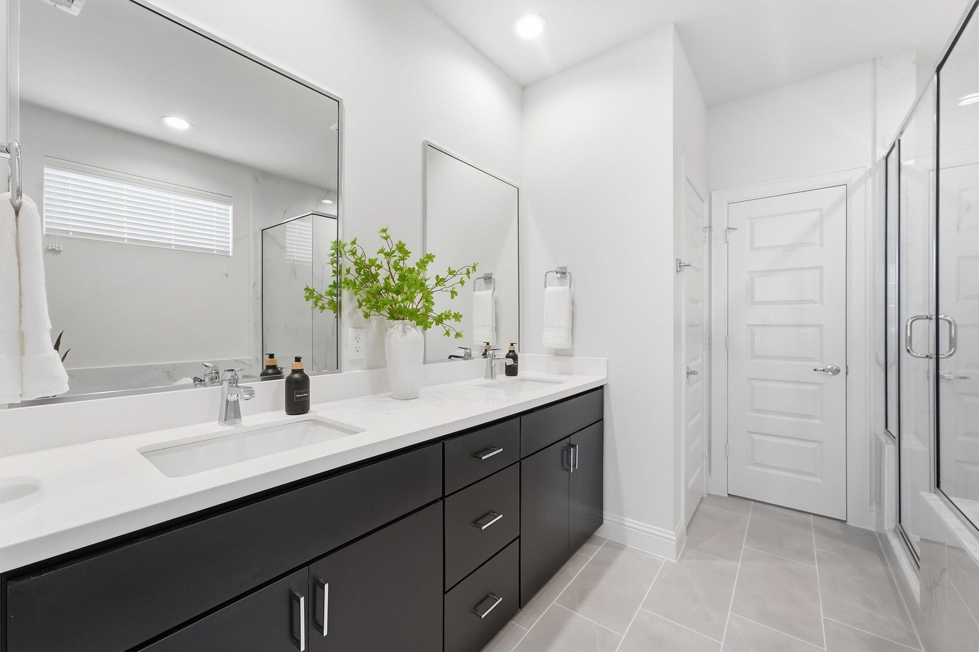 Indulge in luxury with this spacious primary bathroom, boasting a sleek double vanity, elegant finishes, and a glass-enclosed shower for a true spa-like retreat.