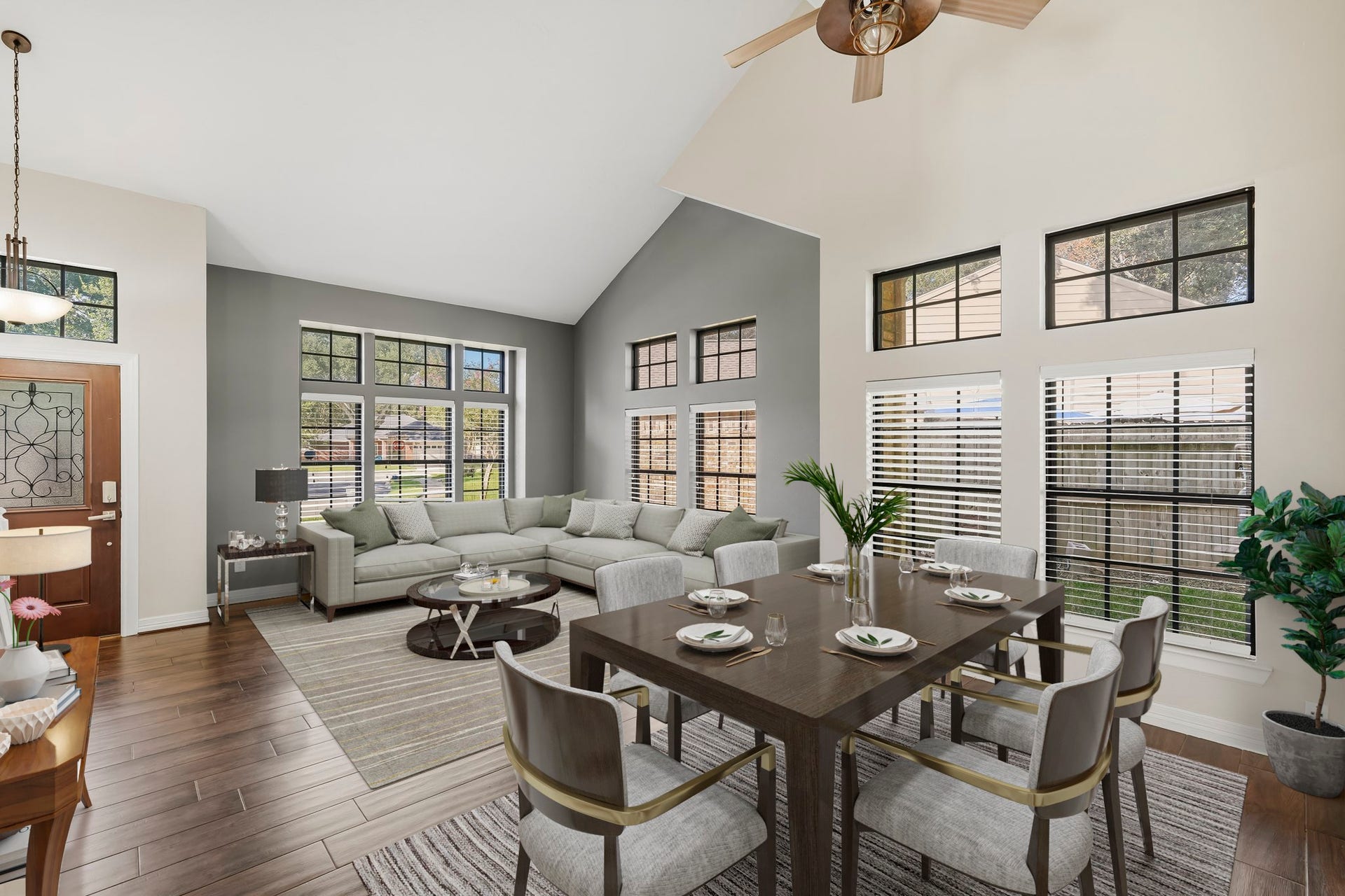3311 Richmond Ferry Court, Richmond, TX 77406 Virtually Staged: This bright, open living and dining area features soaring vaulted ceilings, warm wood-look flooring, and an abundance of natural light from multiple large windows.