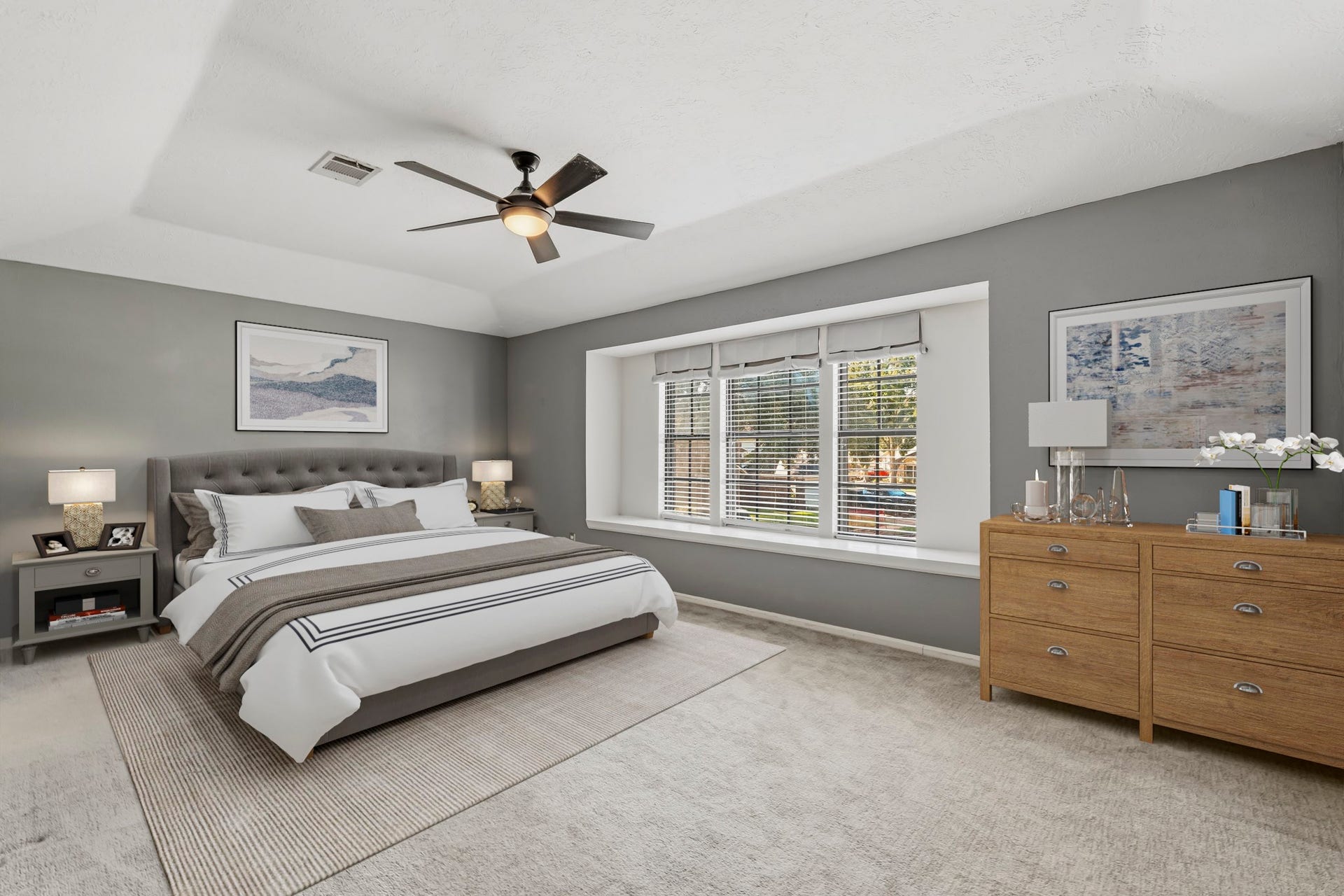3311 Richmond Ferry Court, Richmond, TX 77406 Virtually Staged: This spacious primary bedroom offers a relaxing retreat with soft neutral tones, plush carpeting, and a tray ceiling with a modern ceiling fan. A large trio of windows fills the room with natural light, while the generous floor plan provides plenty of space for a full bedroom suite and additional seating or furniture.