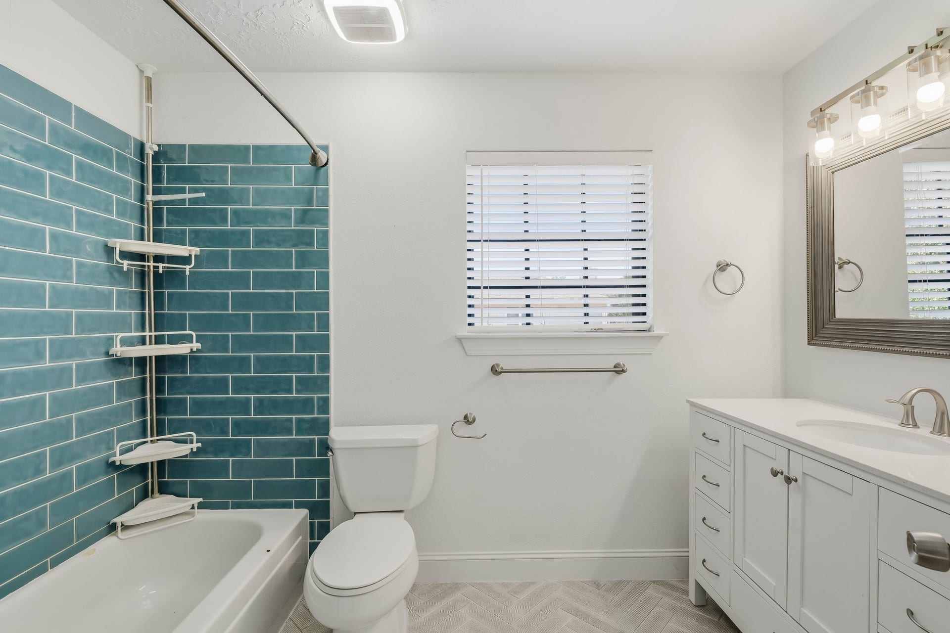 3311 Richmond Ferry Court, Richmond, TX 77406 This bright full bathroom features a tub-and-shower combination accented by striking blue subway tile for a fresh pop of color. A white vanity offers generous storage and counter space, while a large framed mirror, modern lighting, and a window provide a bright, airy feel. Neutral patterned flooring completes the clean and inviting design.