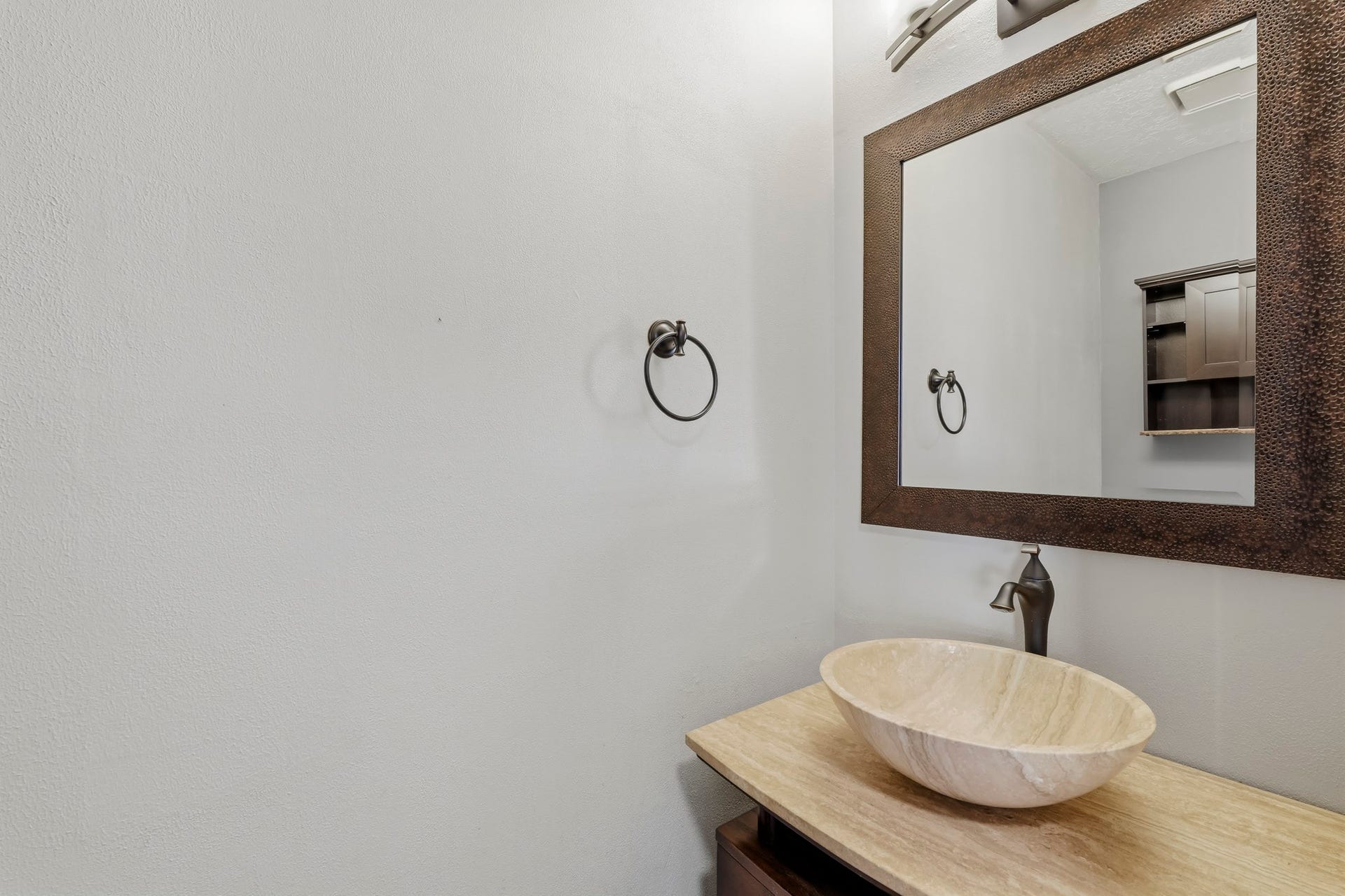 3311 Richmond Ferry Court, Richmond, TX 77406 This stylish half bath features a distinctive stone vessel sink paired with a dark bronze faucet and a warm-toned countertop. An oversized framed mirror, coordinating bronze fixtures, and neutral finishes create a polished, inviting space for guests.
