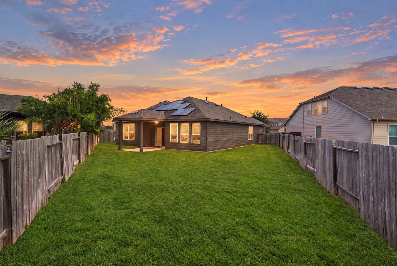 2307 Northern Great White Court, Katy, TX 77449 This deep backyard offers a expansive, fully fenced lawn providing complete privacy along the property lines. A covered patio area extends from the rear facade, while rooftop solar panels add energy-efficient utility to the home.