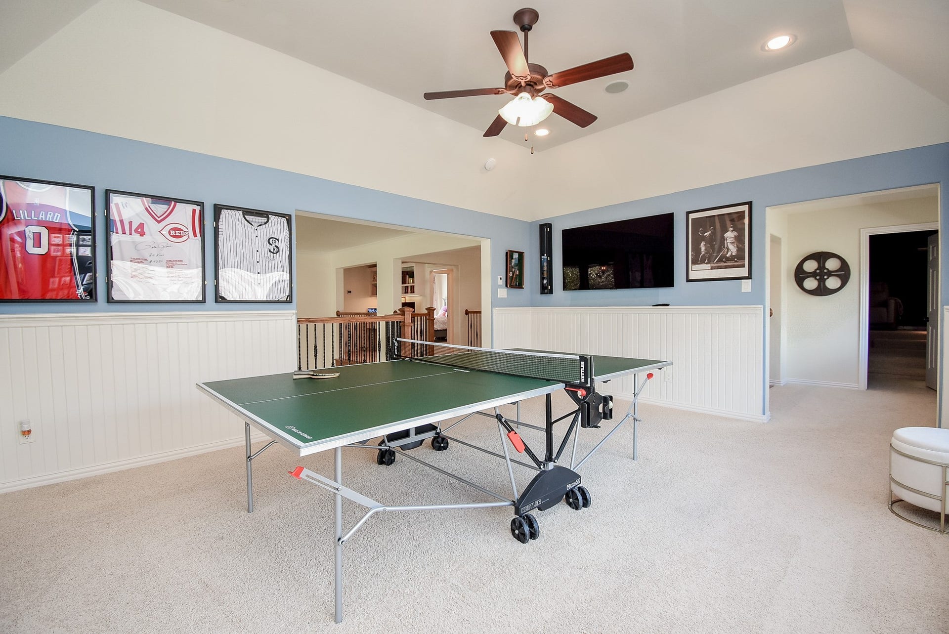 Game room has wainscotting, a gambrel ceiling and plenty of natural lighting.