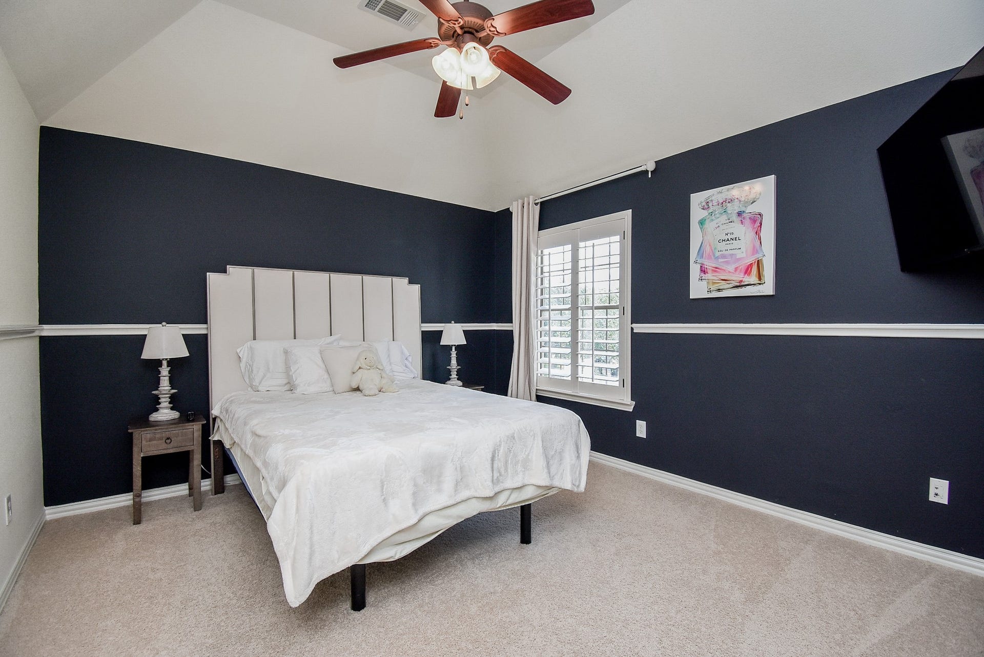 Bedroom two is accented with contrasting wall color, raised ceiling, plantation shutters and chair rail molding.