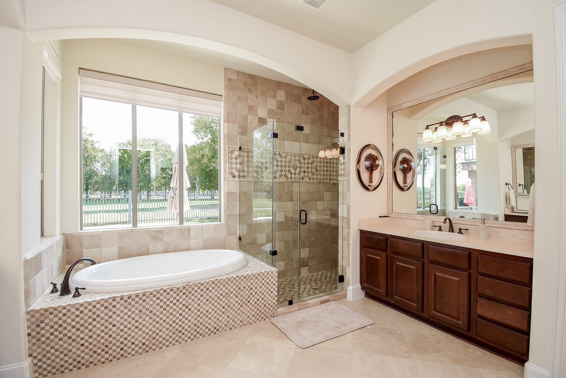 The views in this home just don't stop. Primary suite with soaking tub, frameless shower and two large vanities one of which is shown in this photo. The arches add architectural detail to the room.