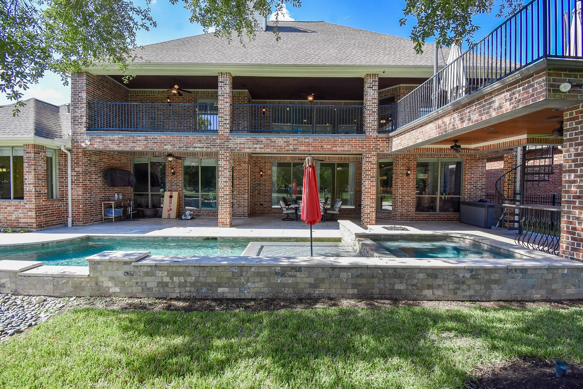 the back exterior with views of the patio, pool/spa and balcony.