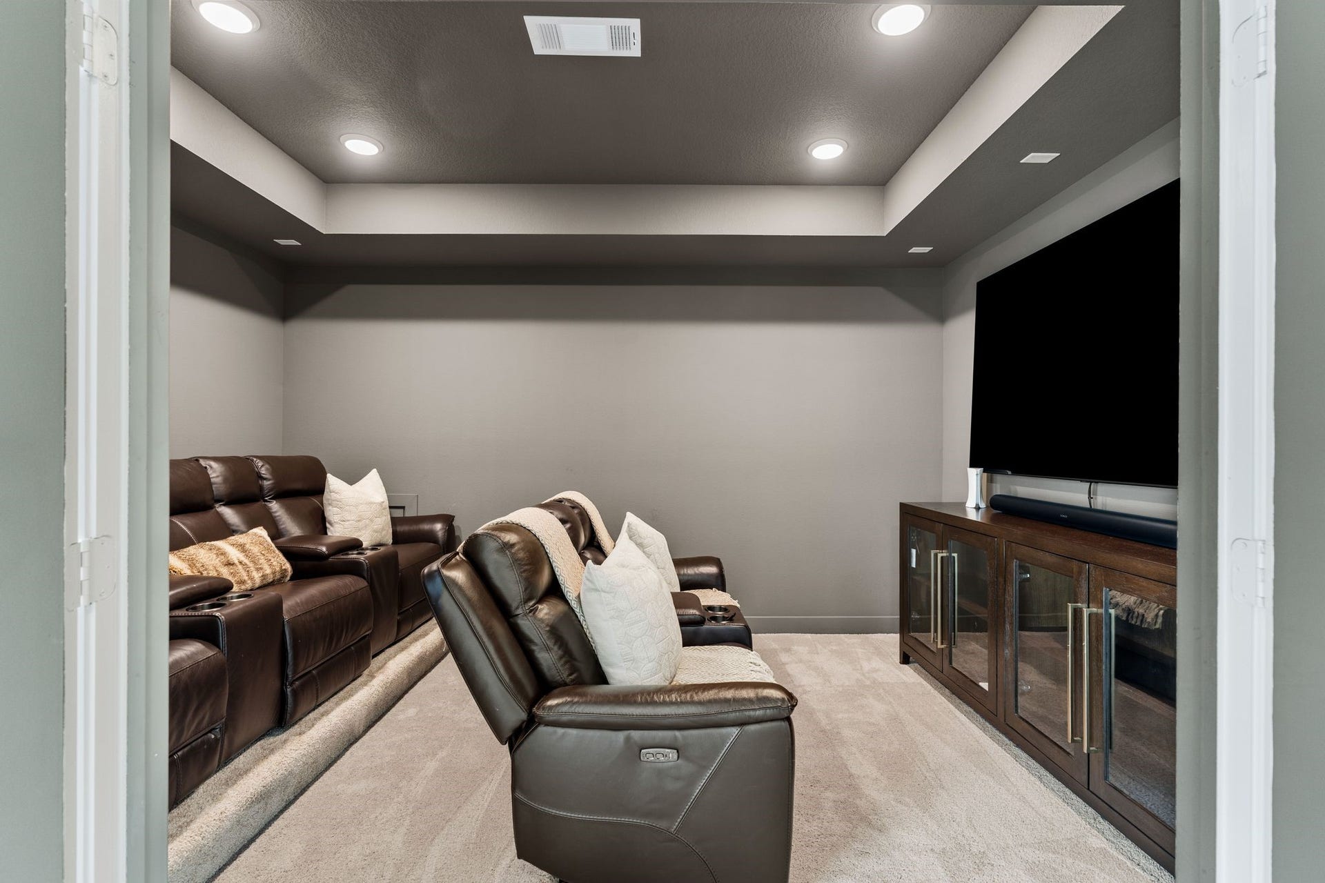 Dedicated media room featuring dramatic tray ceilings, recessed lighting, plush carpeting, and a cozy theater-style settingperfect for movie nights, game days, and entertaining family & friends!
