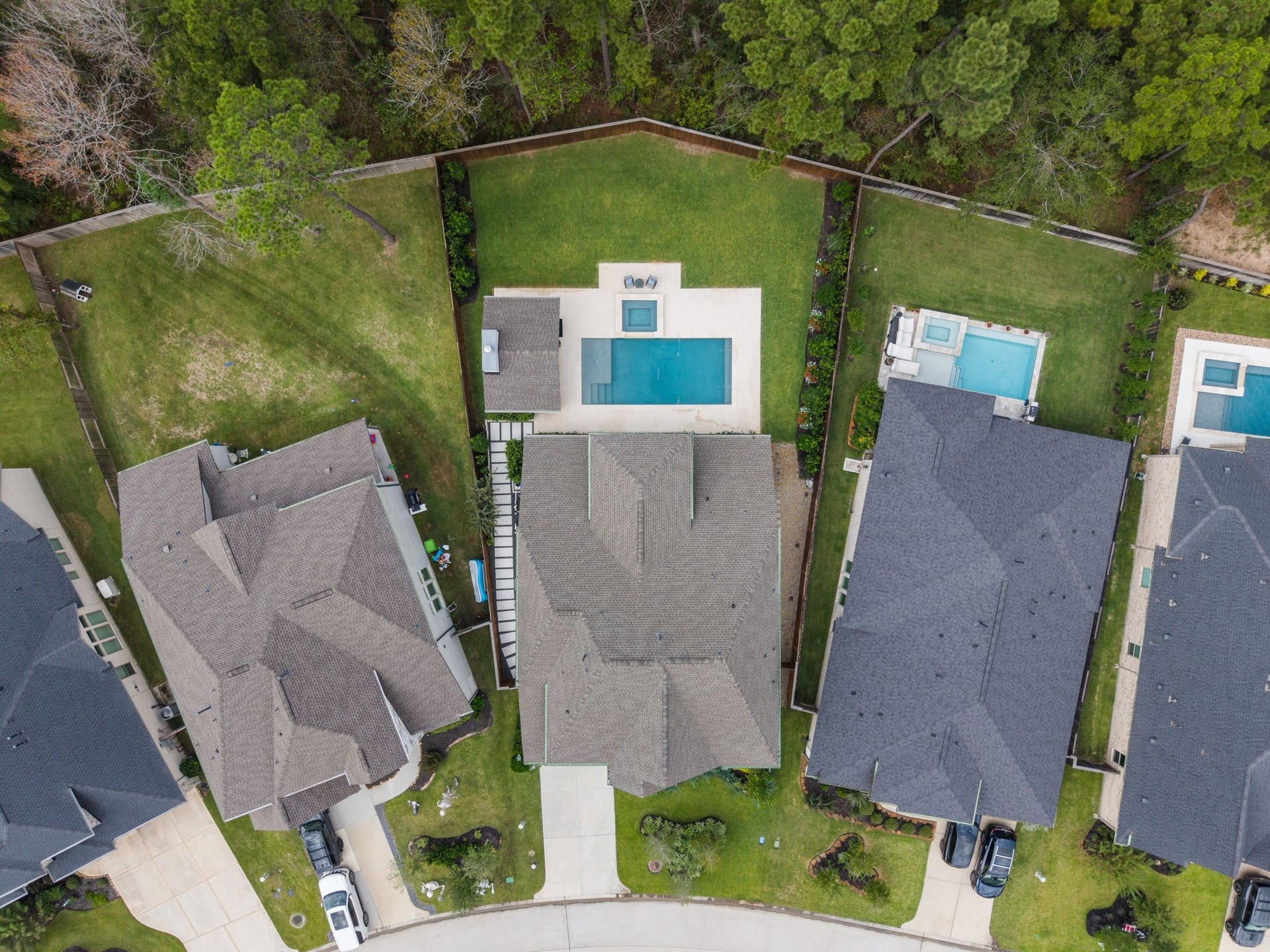 Aerial views highlight the homes impressive oversized homesite, custom professional hardscaping along the side yard, and a wooded easement behind the property that enhances privacywhile still offering an expansive lawn beyond the pool, spa, and cabana for added space to play, relax, and entertain.