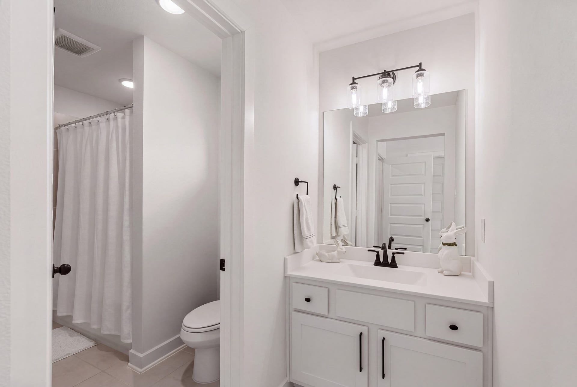 Conveniently designed Hollywood-style bath featuring private vanity areas, elegant quartz countertops, designer lighting, and stylish dark fixturesoffering both comfort and functionality for the upstairs bedrooms!