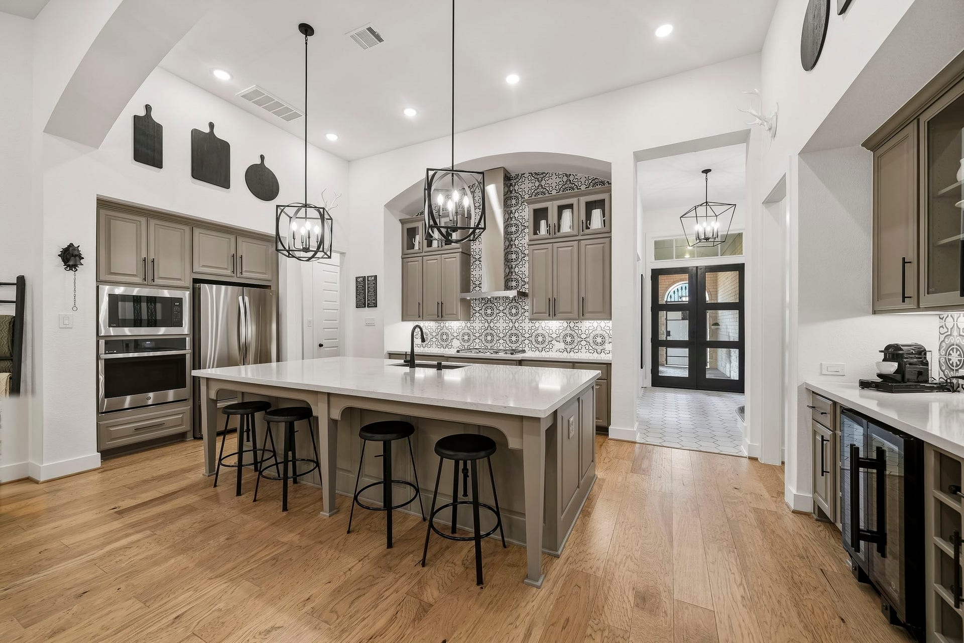 2514 Heritage Park Drive, Missouri City, TX 77459 The kitchens dramatic ceiling-height and decorative tile back splash pairs with elegant glass-front display cabinetry, while statement pendant lighting adds a sophisticated glow and elevates the kitchens custom, high-end design.