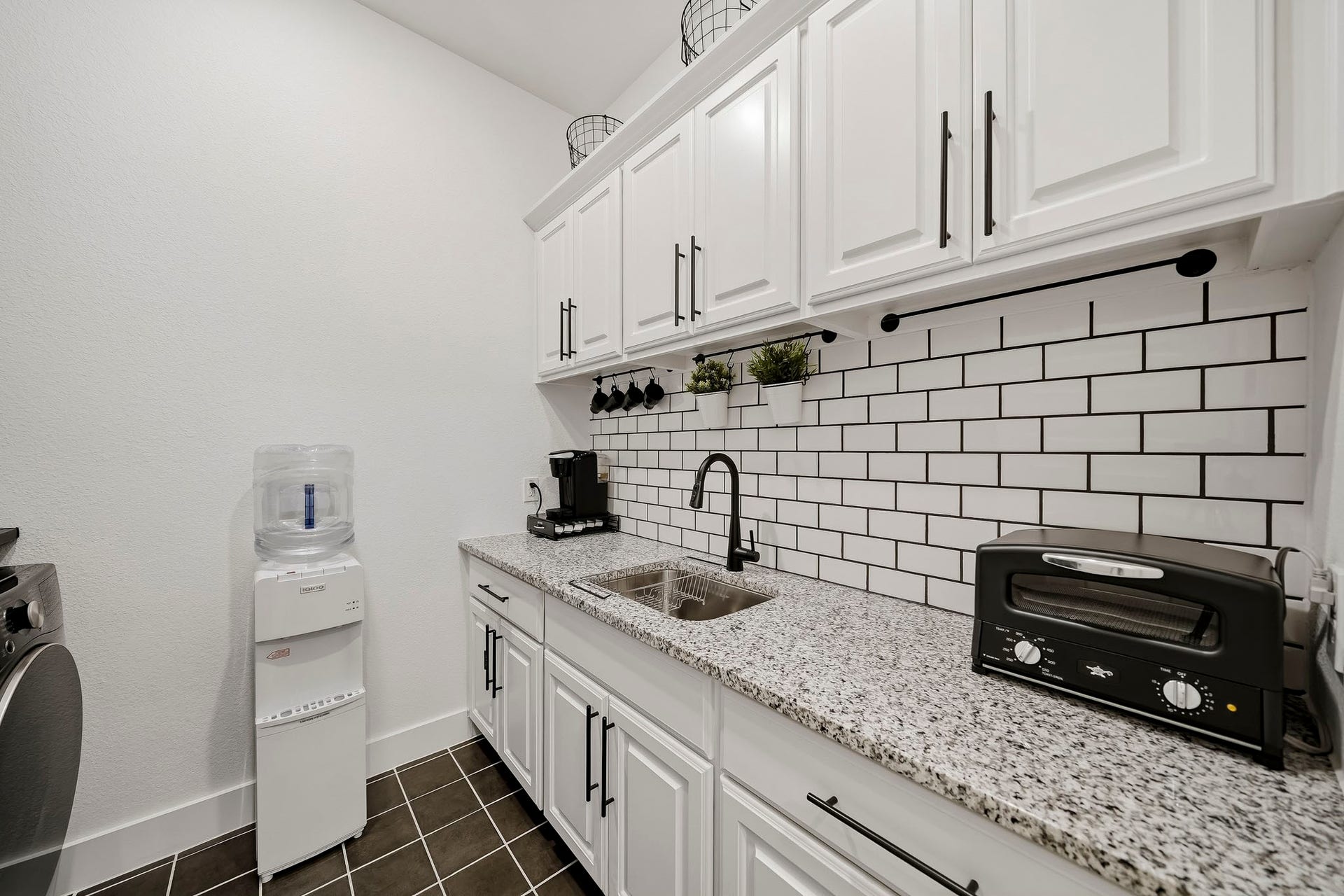 2514 Heritage Park Drive, Missouri City, TX 77459 Upper and lower cabinetry provides abundant storage, while a granite countertop and classic subway tile back splash elevate the space. Designed for versatility, this well-appointed utility room also serves beautifully as a dedicated coffee bar, butler's pantry or an electronic station.