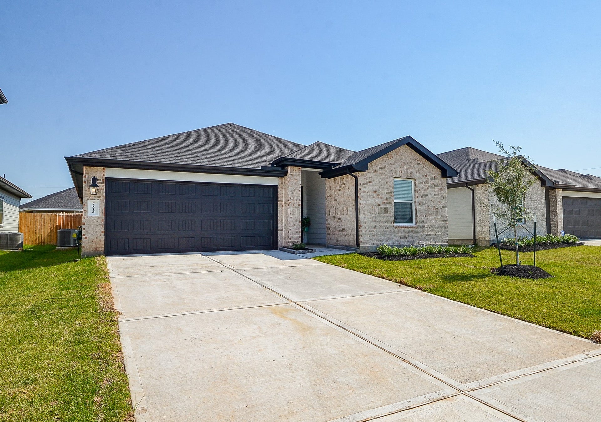 7814 Bel Fiore Drive, Richmond, TX 77406 Charming single-story home featuring a modern brick exterior, sleek dark garage door, and a spacious driveway, set on a beautifully manicured lawn.