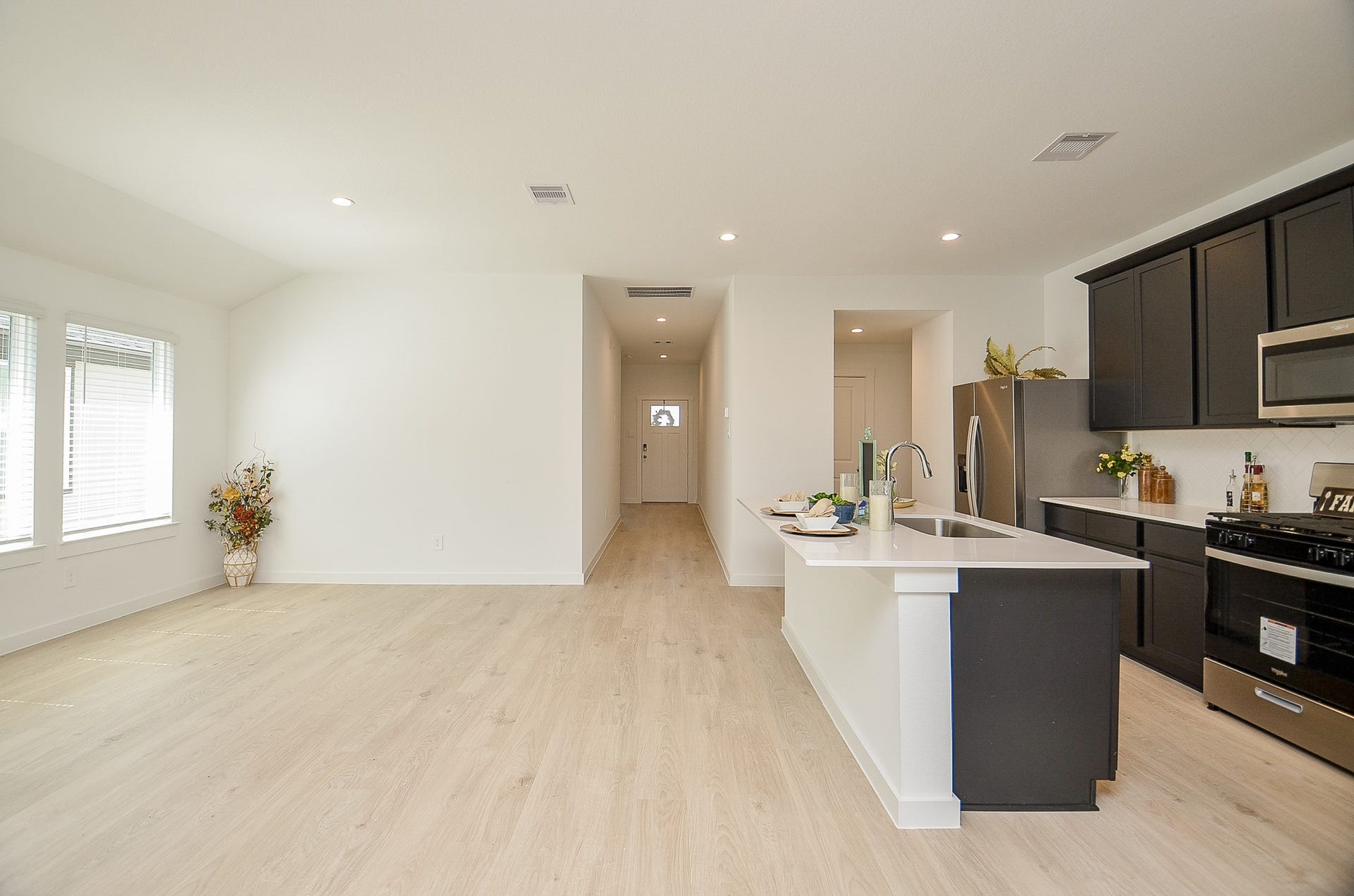 7814 Bel Fiore Drive, Richmond, TX 77406 Spacious open-concept kitchen and living area featuring sleek dark cabinetry, modern appliances, and ample natural light from large windows.