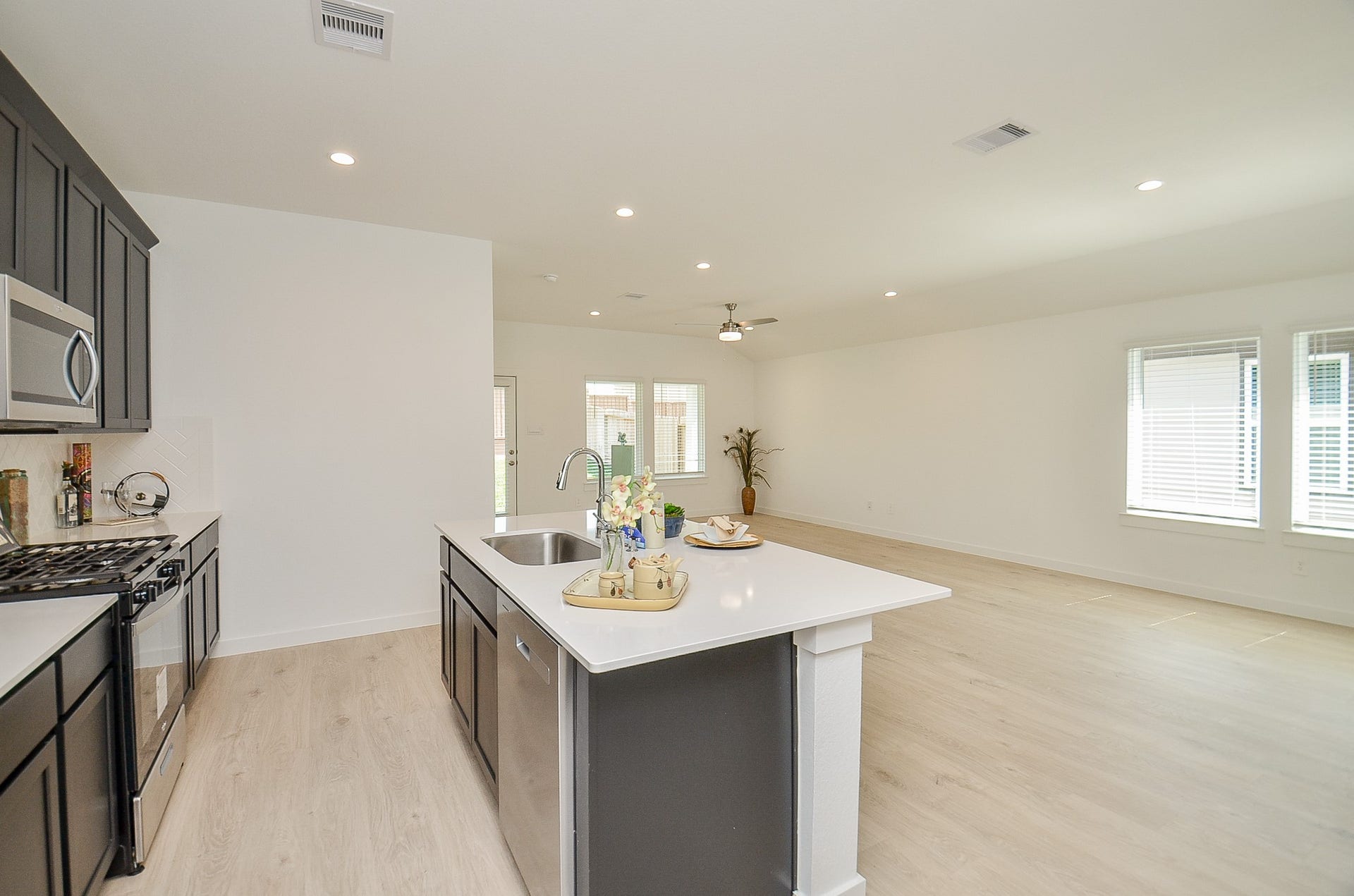 7814 Bel Fiore Drive, Richmond, TX 77406 Bright and spacious open-concept kitchen and living area featuring sleek dark cabinetry, modern stainless steel appliances, and a large island with ample seating space.