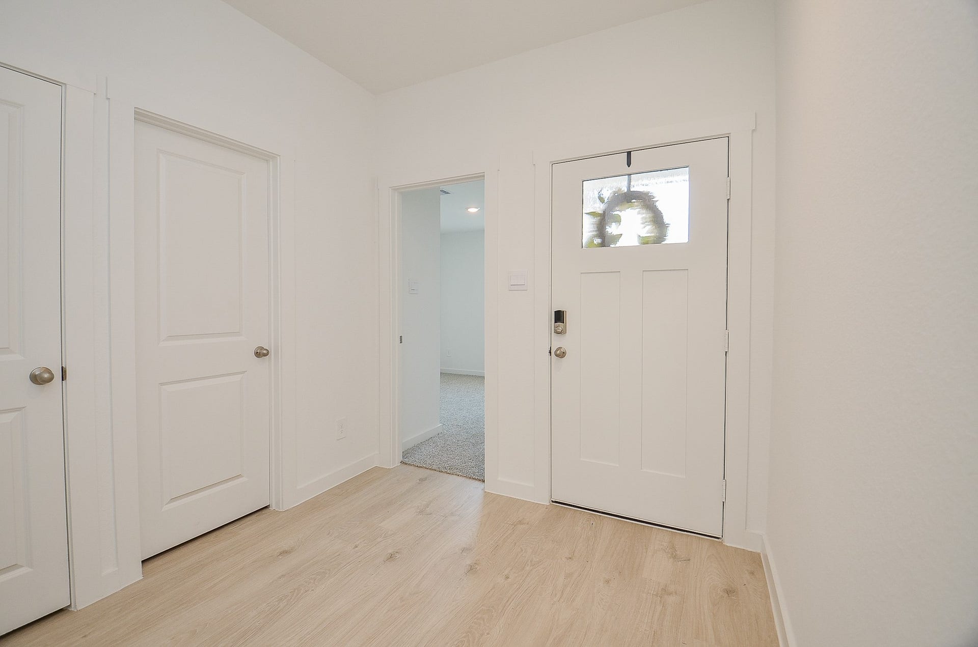 7814 Bel Fiore Drive, Richmond, TX 77406 Bright and welcoming entryway featuring modern white doors, sleek hardware, and light wood flooring.