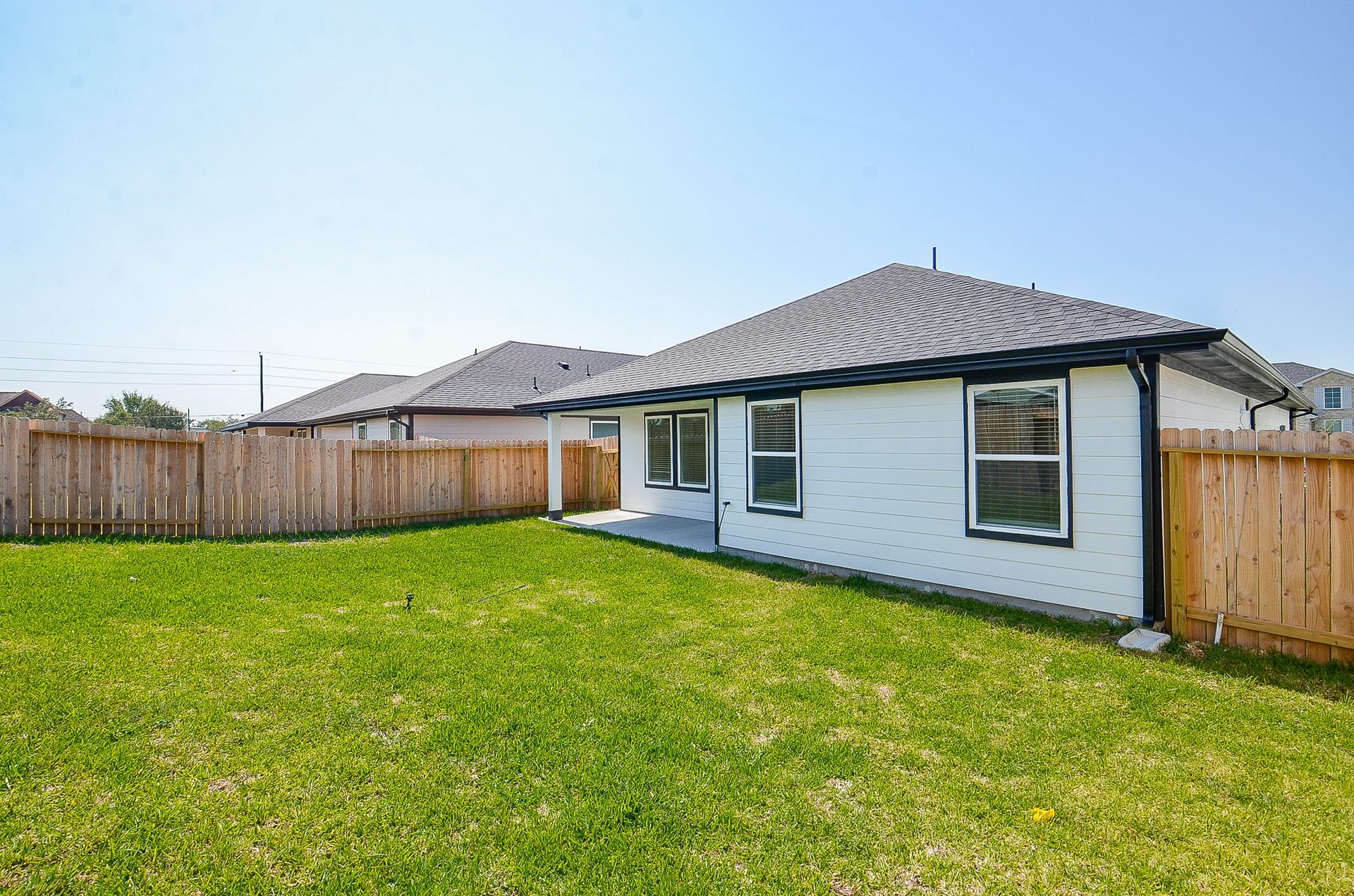 7814 Bel Fiore Drive, Richmond, TX 77406 Spacious backyard with lush green grass and a wooden fence, perfect for outdoor activities and privacy.