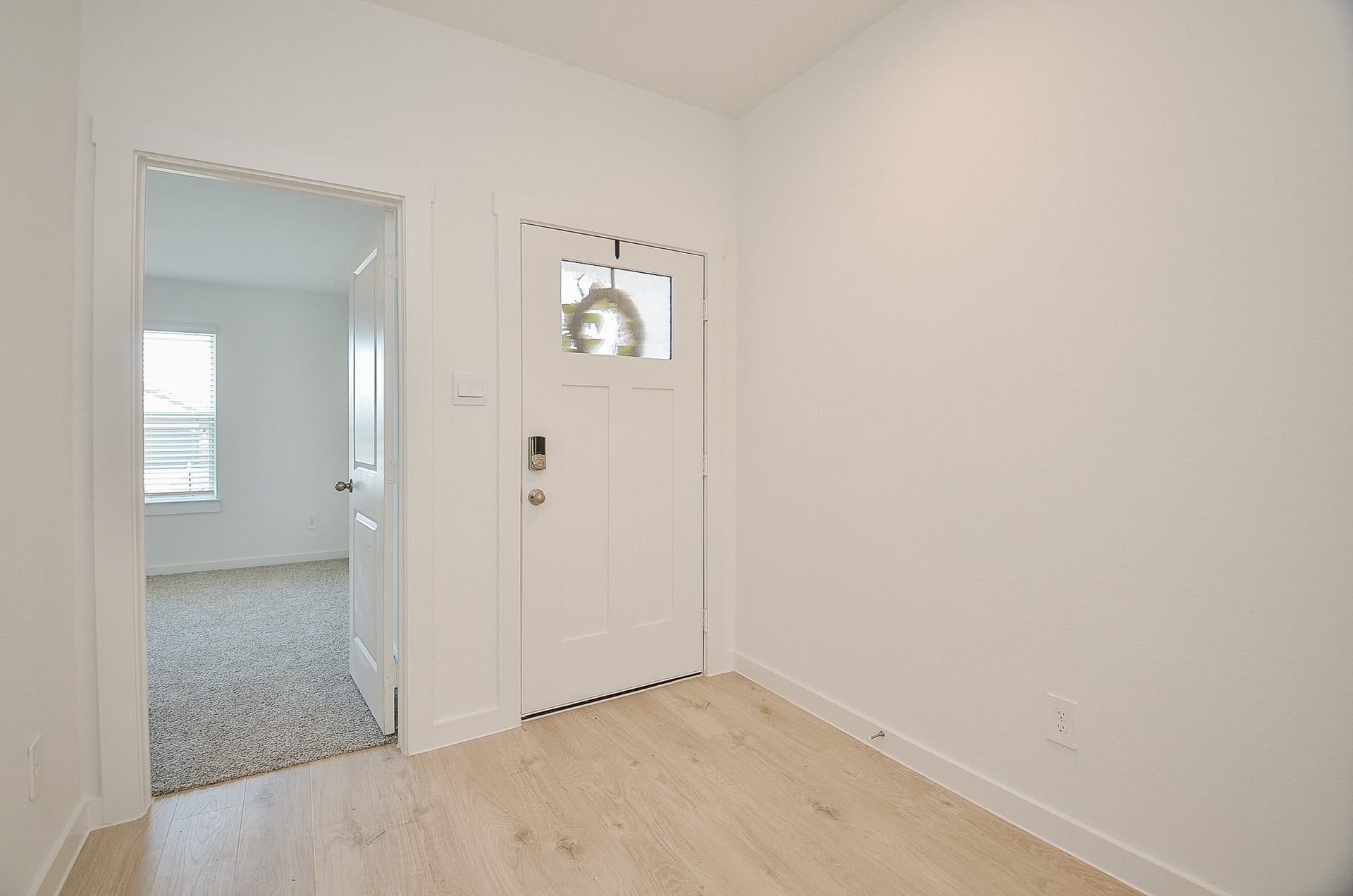 7814 Bel Fiore Drive, Richmond, TX 77406 Bright and inviting entryway with light wood flooring and a classic white front door, leading into a cozy, carpeted room with ample natural light.