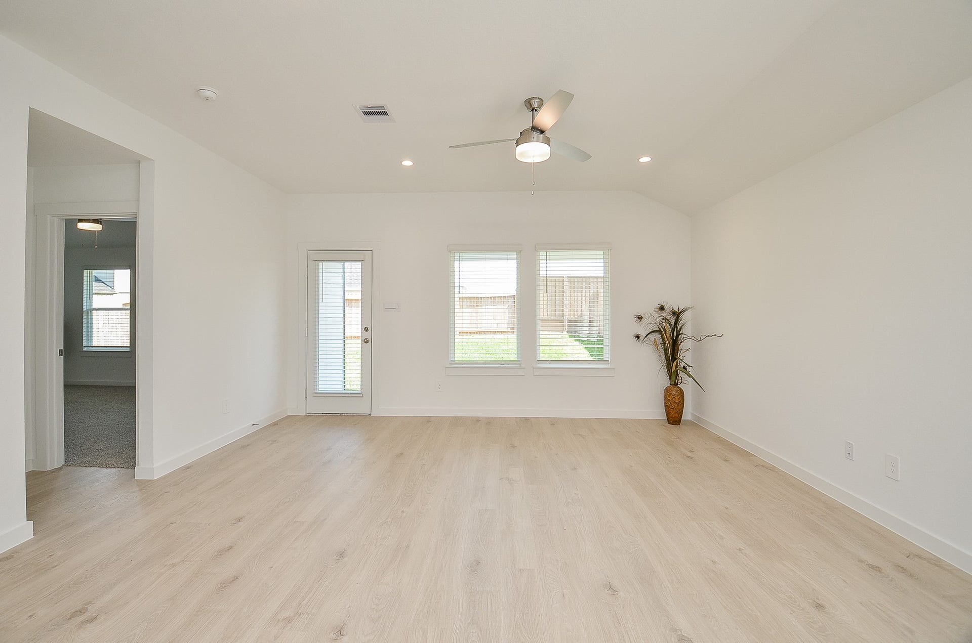 7814 Bel Fiore Drive, Richmond, TX 77406 Bright and spacious living area with light wood flooring, large windows, and a ceiling fan, offering ample natural light and a seamless indoor-outdoor flow.