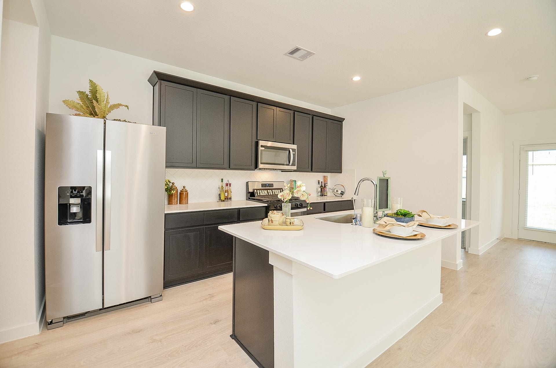 7814 Bel Fiore Drive, Richmond, TX 77406 Modern kitchen with sleek dark cabinetry, stainless steel appliances, and a spacious white island perfect for dining and entertaining.