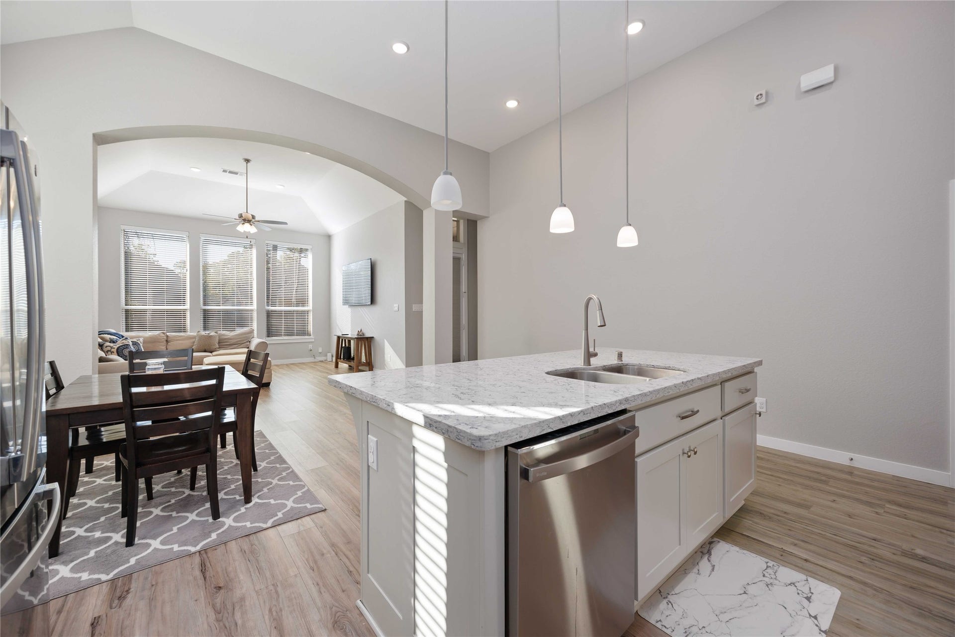 12610 Woodbourne Forest Drive, Humble, TX 77346 Modern open-concept living space featuring a stylish kitchen with a marble countertop island, stainless steel appliances, and pendant lighting. The adjacent dining and living area offers large windows for ample natural light.
