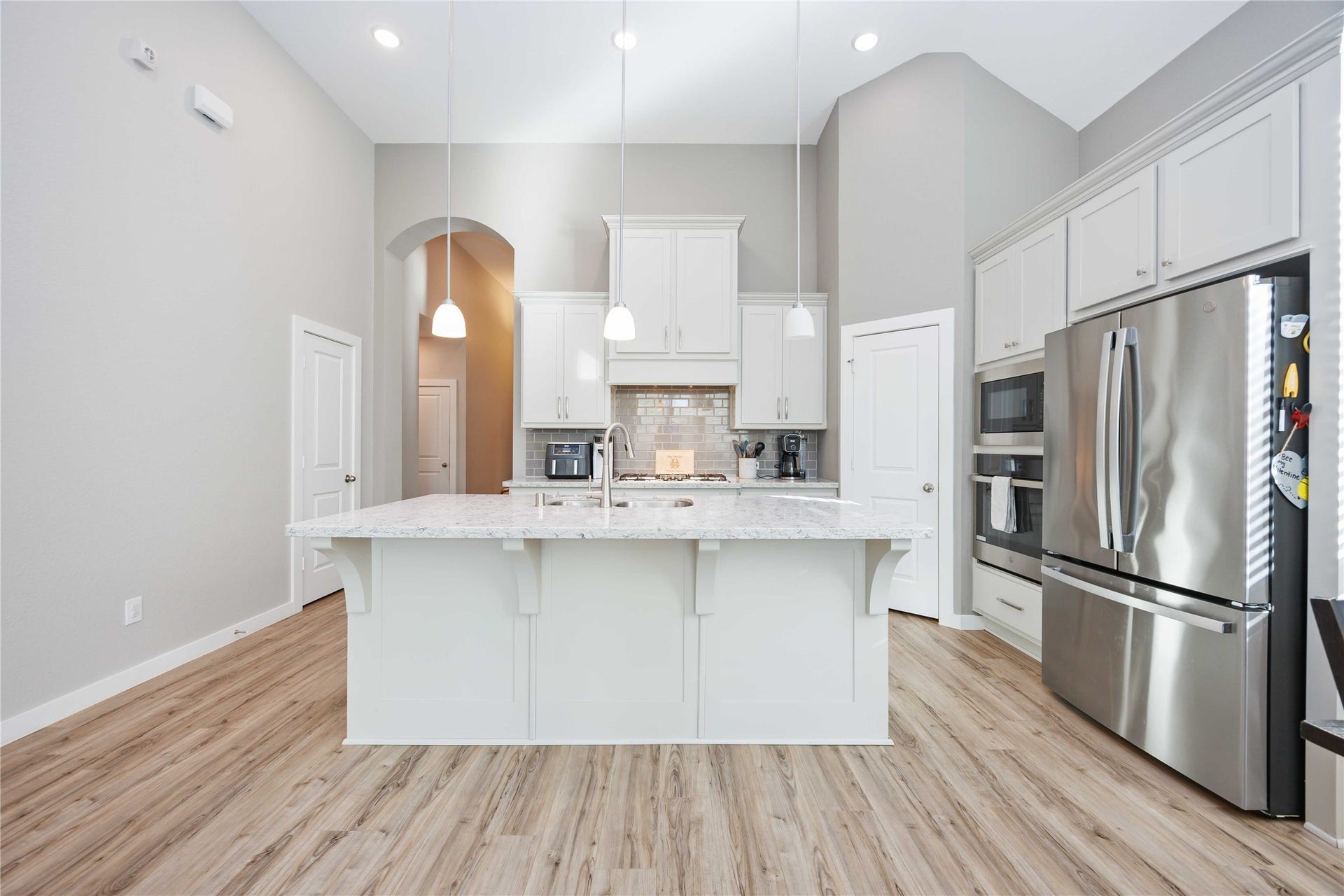12610 Woodbourne Forest Drive, Humble, TX 77346 This kitchen features a spacious, modern design with high ceilings and ample lighting. It includes a large island with a marble countertop, stainless steel appliances, and sleek white cabinetry for a clean, elegant look.