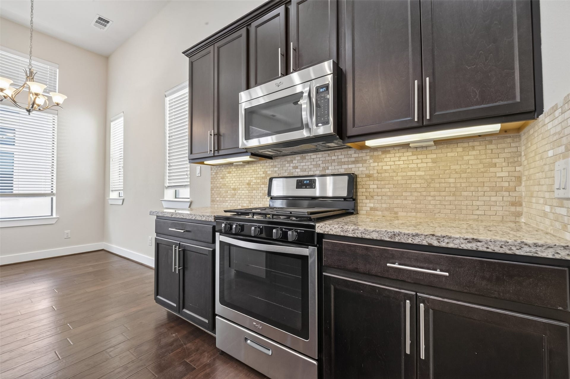 40 N Hutcheson Street, Houston, TX 77003 Modern kitchen with sleek dark cabinets, stainless steel appliances, and a stylish tile backsplash, complemented by warm hardwood floors and ample natural light.