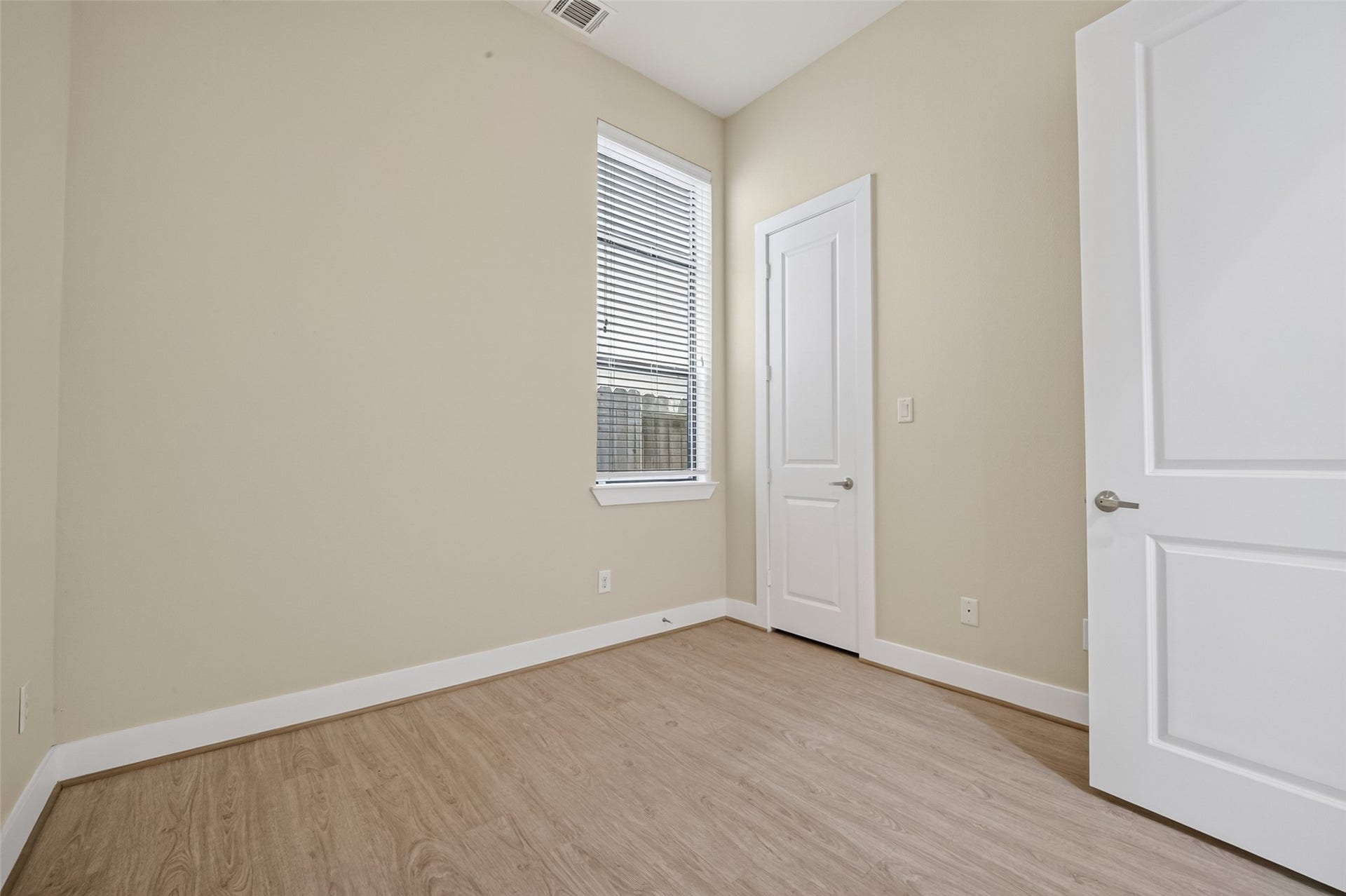 40 N Hutcheson Street, Houston, TX 77003 Bright and inviting room with sleek LVP flooring, neutral walls, and a tall window that offers ample natural light, perfect for a cozy retreat or functional office space.